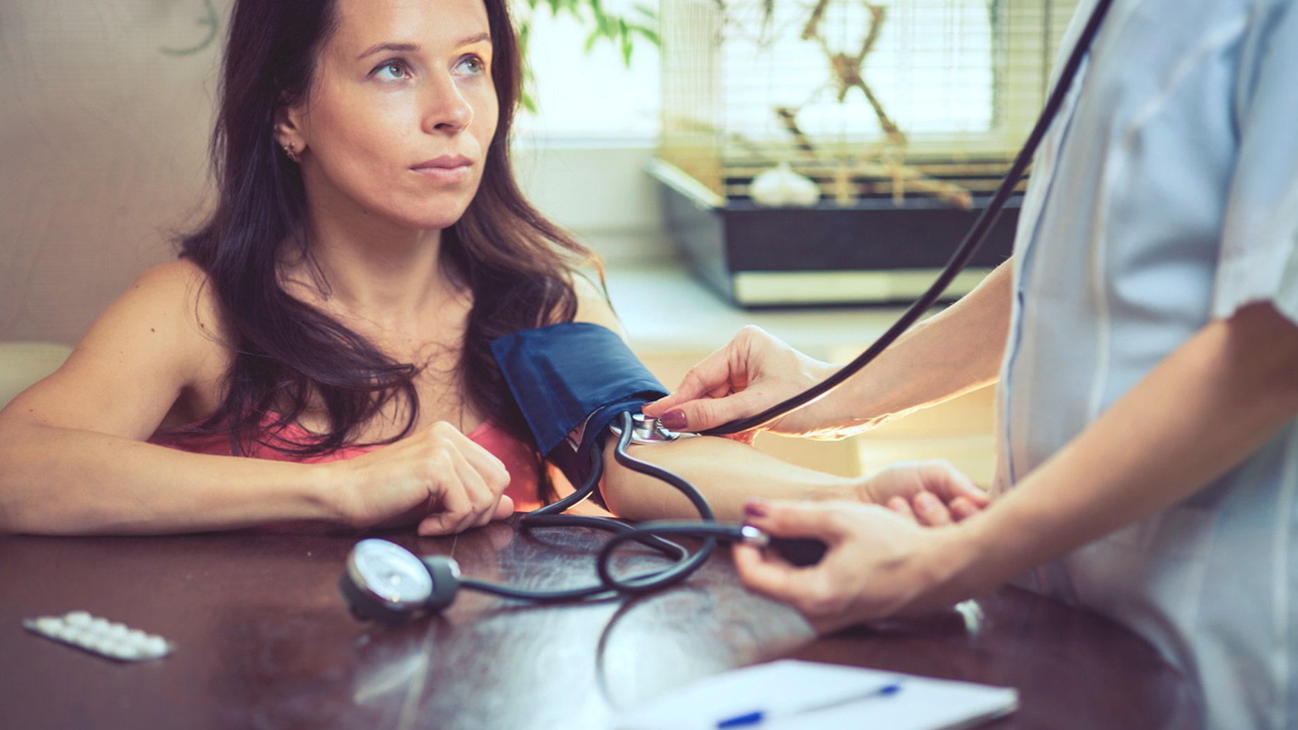 Beautiful young female doctor is checking the blood pressure of the patient.