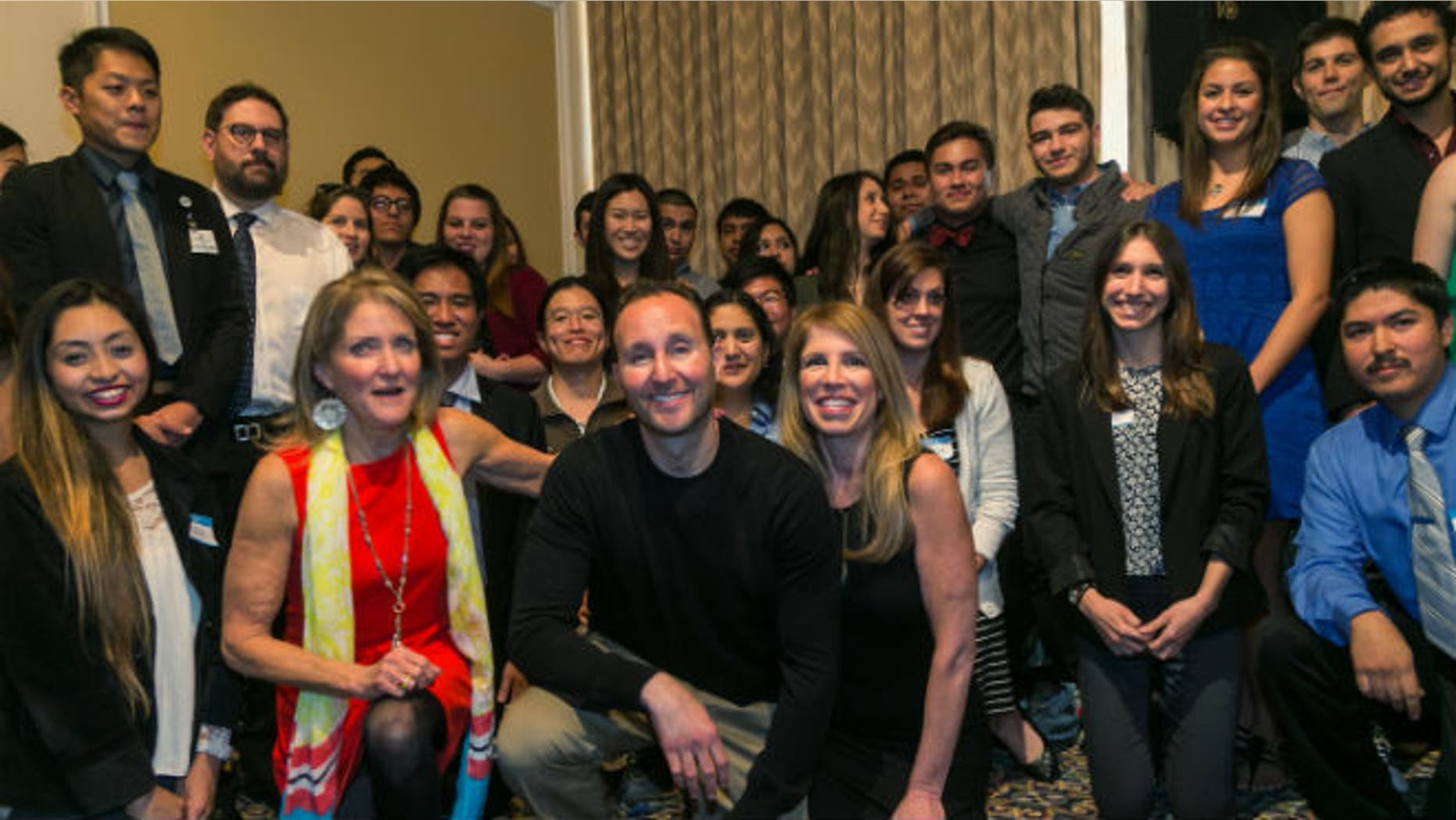 Motorcycle crash victim Brandon Levine, first row kneeling center, poses with Glendale High School students, part of the hundreds of donors of the 207 units of blood, plasma and platelets that preserved his life after a devastating motorcycle accident on April 27, 2014, that left him comatose for a month, during a ceremony at the UCLA campus in Los Angeles on Friday, Jan. 30, 2015. Next to him,at left, his mother, Betsy Sachs and his girlfriend, Leigh Horwitz. (AP Photo/Damian Dovarganes)