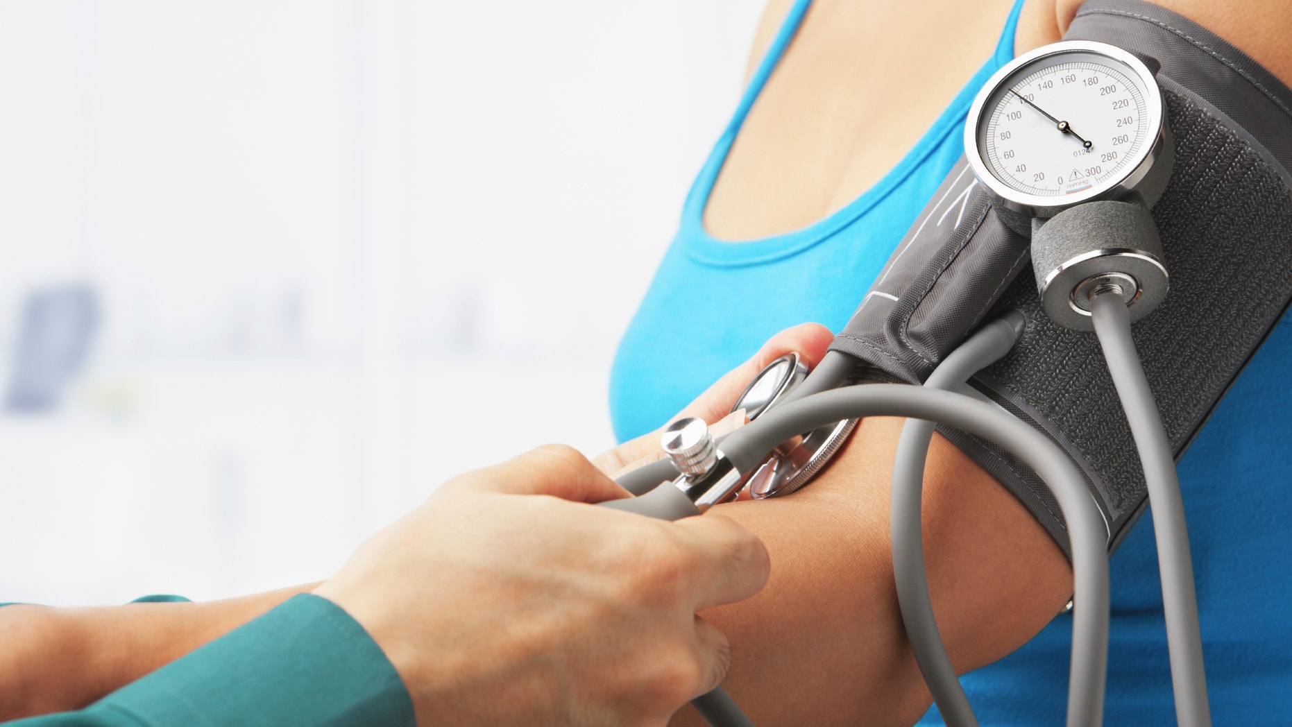 Checking blood pressure of female patient, unrecognizable people