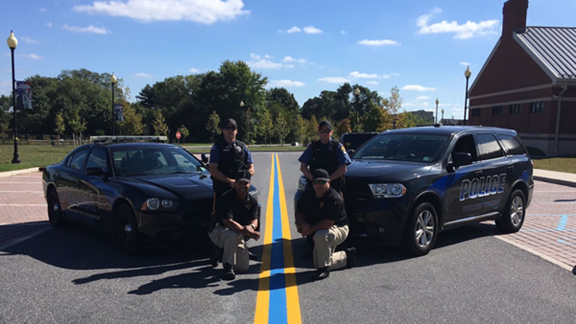 Police officers in Woolwich Twp., NJ pose with a blue line tribute painted last October.