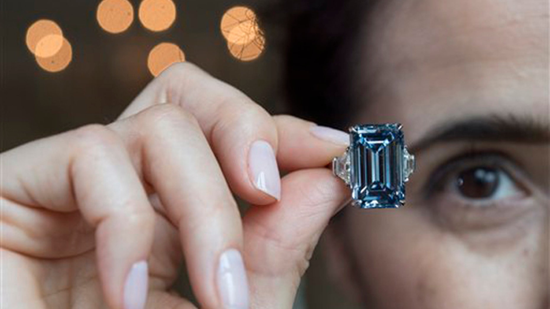 A Christie's employee holds Oppenheimer Blue diamond of 14.62 carats, which is estimated to be sold between 38,000,000 to 45,000,000 US Dollar, during a preview at the auction house Christie's, in Geneva, Switzerland, Thursday, May 12, 2016. The auction will take place on May 18, 2016 in Geneva. (Martial Trezzini/Keystone via AP)
