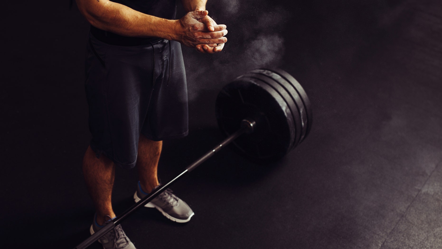 Athlete clapping hands with talc before deadlift barbells workout