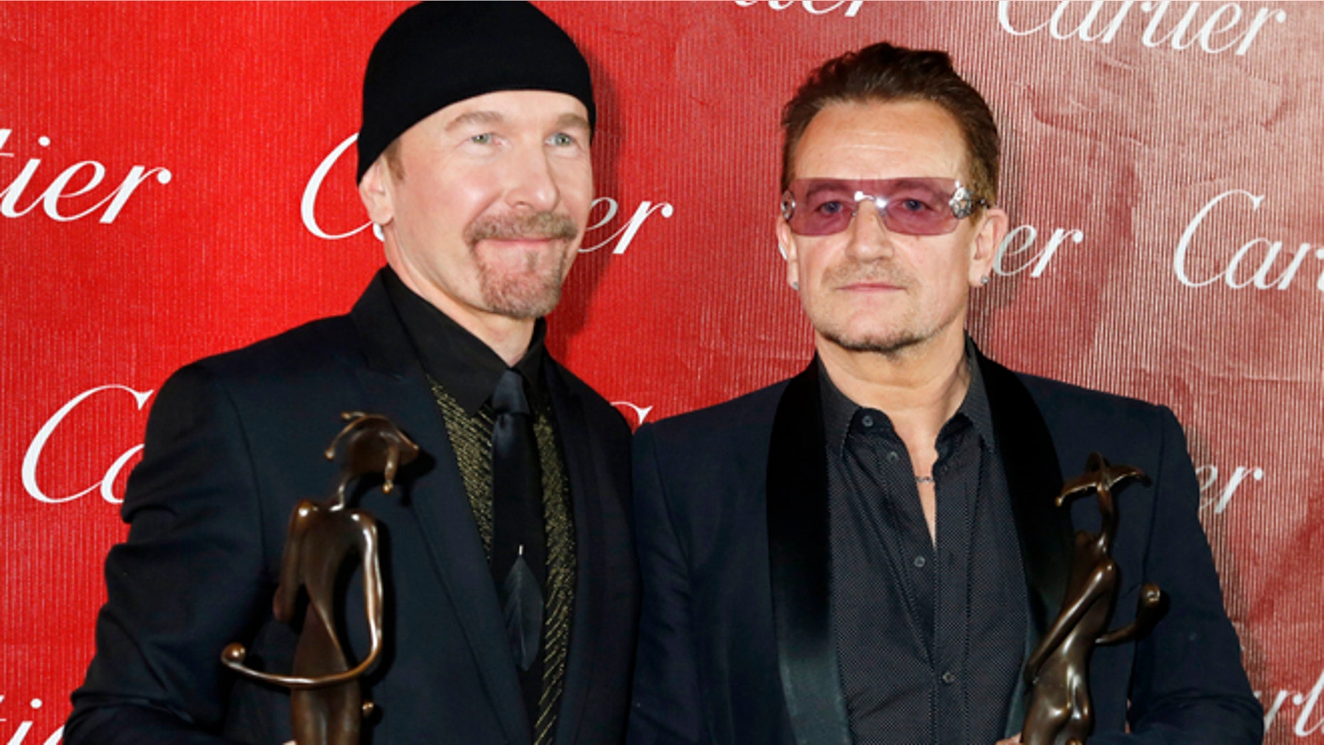 Bono (R) and the Edge of U2 pose backstage with the Sonny Bono Visionary Award they received at the 2014 Palm Springs International Film Festival Awards Gala in Palm Springs, California January 4, 2014. REUTERS/Fred Prouser (UNITED STATES - Tags: ENTERTAINMENT) - RTX172NH