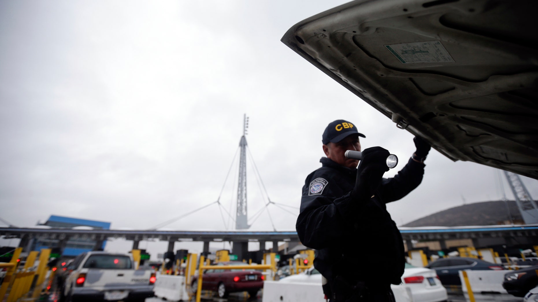 In this Dec. 3, 2014 file photo, a U.S. Customs and Border Protection (CBP) officer checks under the hood of a car as it waits to enter the United States from Tijuana, Mexico through the San Ysidro port of entry in San Diego. Taking a polygraph became a hiring requirement at CBP in 2012 after a huge hiring surge led to more agents getting arrested for misconduct. (AP Photo/Gregory Bull)