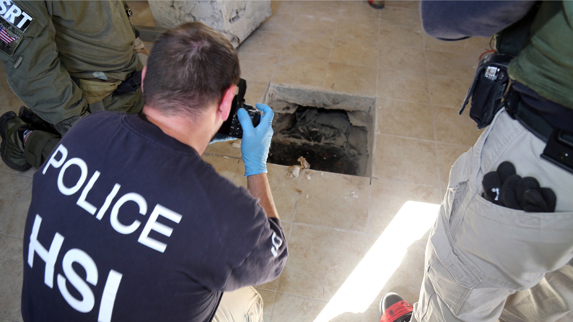 March 23, 2016: This photo provided by U.S. Immigration and Customs Enforcement shows an investigator photographing the terminus of a tunnel at a newly-built home in Calexico, Calif., that runs the length of four football fields to a restaurant in Mexicali, Mexico.
