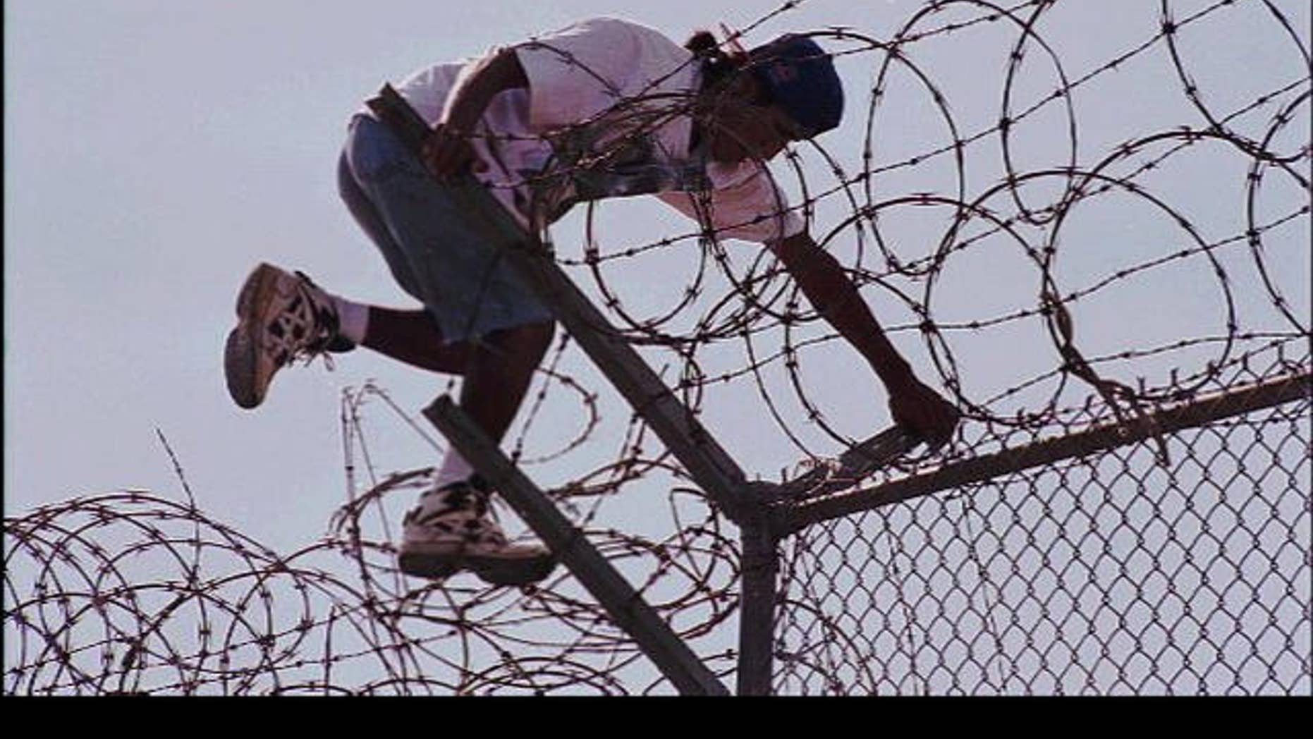 Man climbs over barbed wire at U.S.-Mexico border (AP file photo)