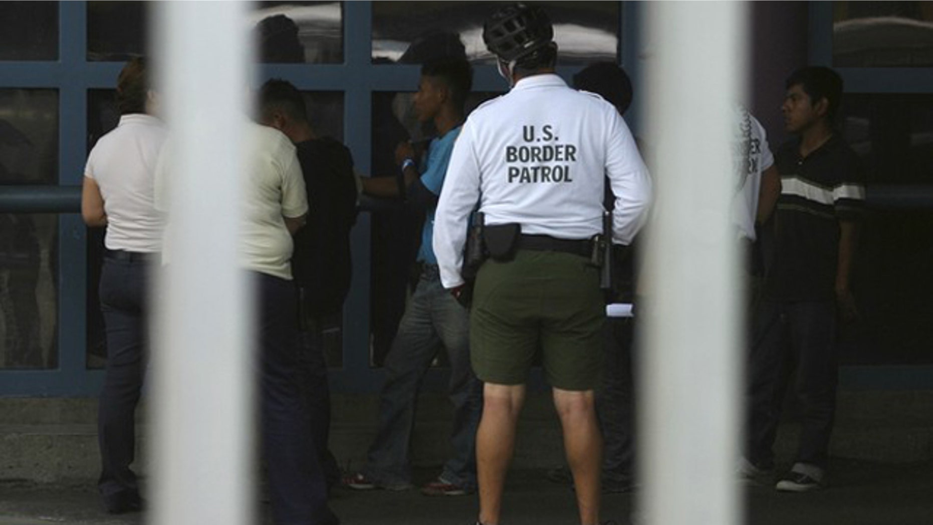 Illegal immigrants stand next to a Border Patrol agent before being deported from Arizona to the Mexican state of Sonora on July 26, 2010.