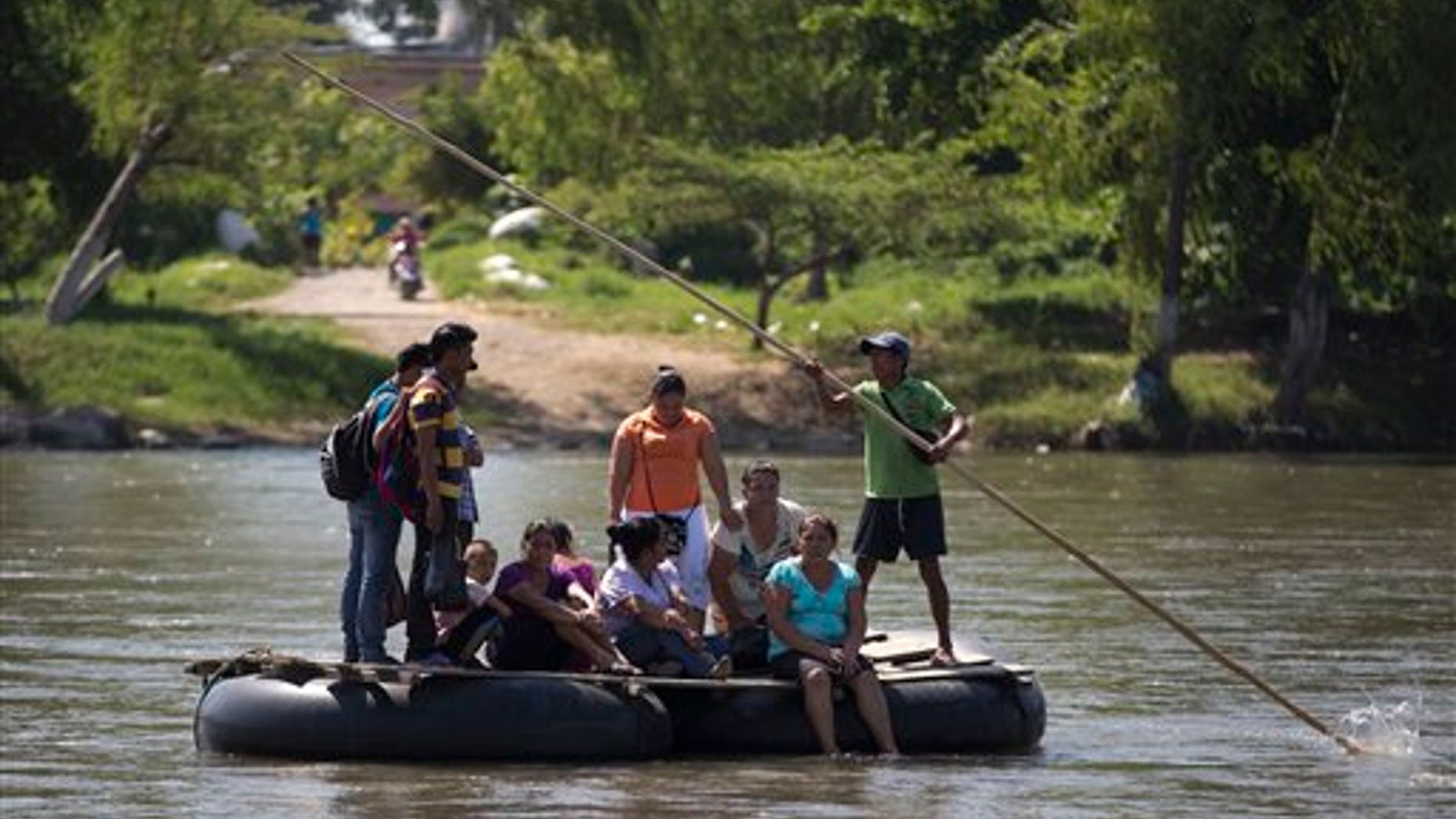 In this July 11, 2014, photo, people are rafted to the Mexican shore, across the Suchiate river that separates Tecun Uman, Guatemala and Ciudad Hidalgo, Mexico, on a makeshift raft. (AP Photo/Eduardo Verdugo)