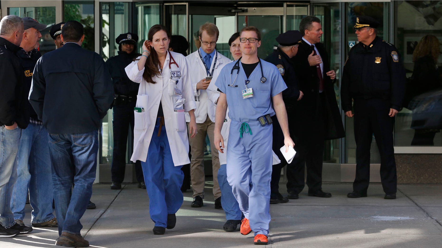 Jan. 20, 2015: Medical personnel walk past law enforcement officials, right, as they depart the Shapiro building at Brigham and Women's Hospital, in Boston.