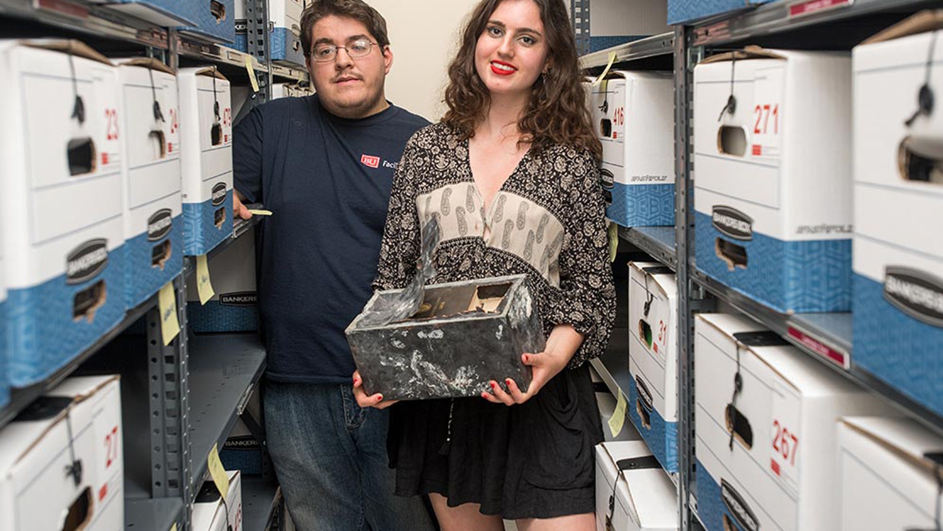 Adam Mumford (CAS’18) and Emma Purtell (CGS’17, COM’19) with the time capsule found in one of the hundreds of boxes of files they were archiving for BU’s Facilities Management & Planning. Photo by Cydney Scott
