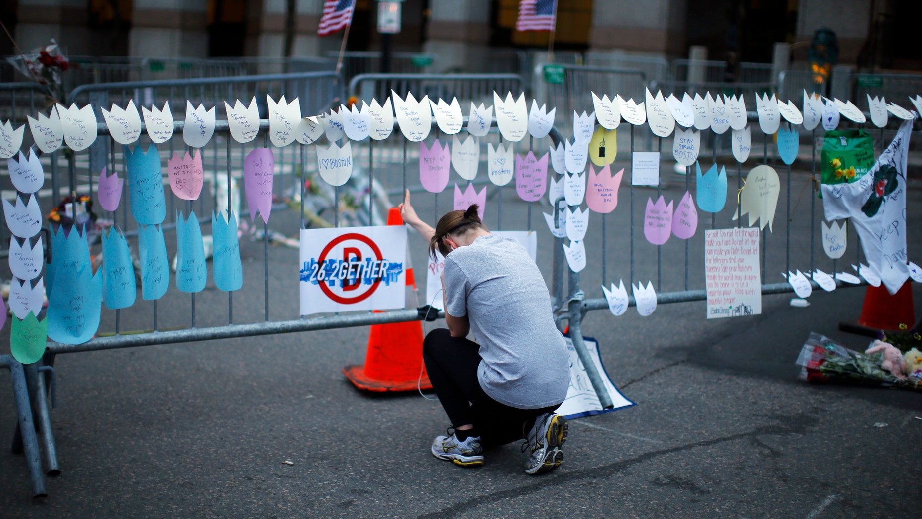A woman kneels and cries in front of a memorial to the Boston Marathon bombings victims, at the barricades surrounding the scene in Boston, Massachusetts April 18, 2013.