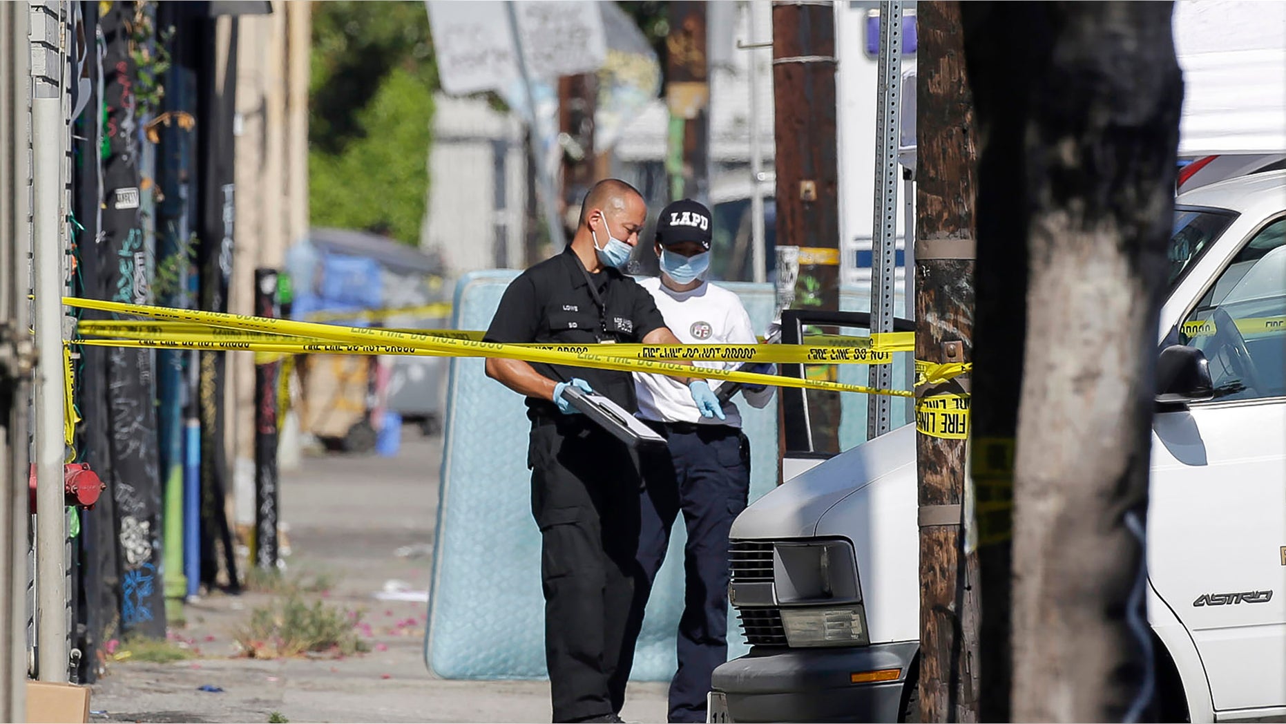 Los Angeles Police Department investigators work at a crime scene, where three children have been found dead inside a car parked outside an elementary school while a man found with them is in critical condition in South Los Angeles Wednesday, Sept. 9, 2015. Officer Jack Richter says the three children were declared dead at the scene while a man found with them was taken to a nearby hospital, also with stab wounds. His relationship to the children wasn't immediately clear. (AP Photo/Nick Ut)