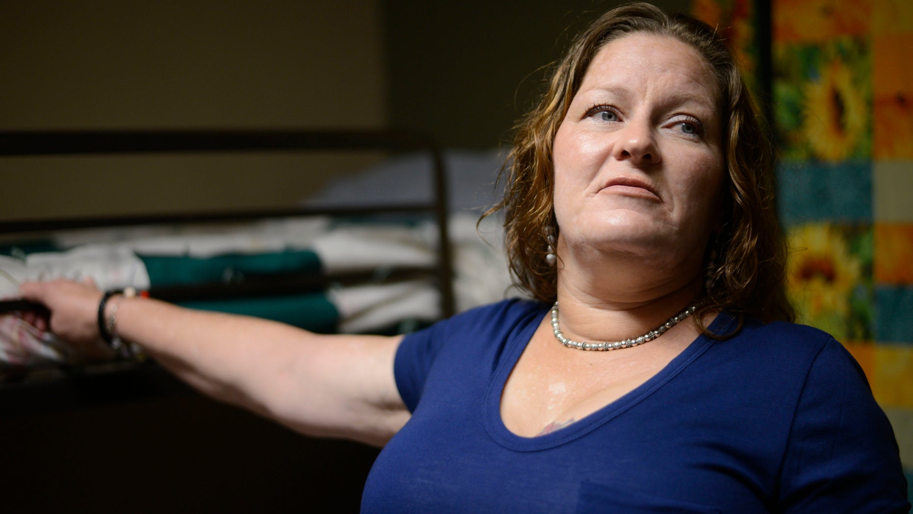 Susan Contreras stands next to her bed in a Phoenix-area shelter for victims of domestic violence on Wednesday, Aug. 3, 2016. Contreras is part of a unique program at the Barrow Neurological Institute in Phoenix that aims to assist abuse survivors who have suffered head trauma. (AP Photo/Beatriz Costa-Lima)