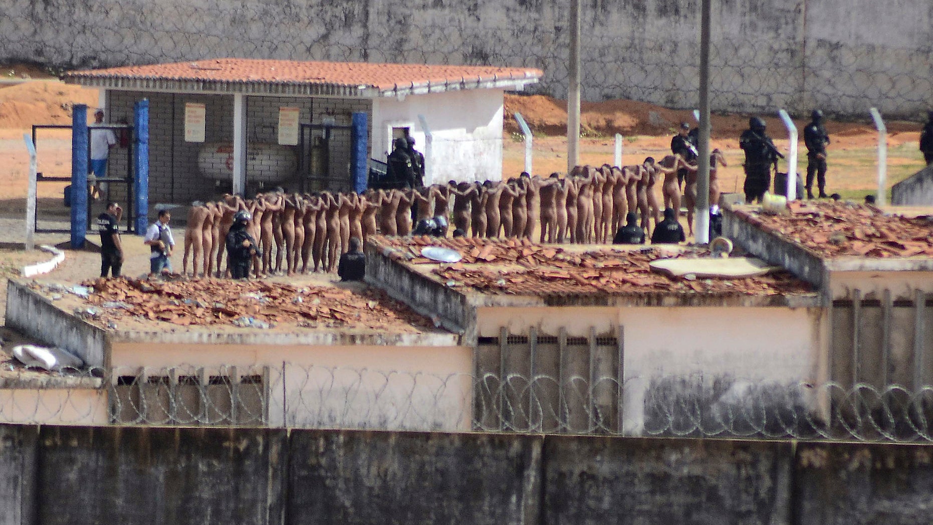 Naked inmates stand in line while surrounded by police after a riot at the Alcacuz prison in Nisia Floresta, Rio Grande do Norte state, Brazil, Sunday, Jan. 15, 2017.