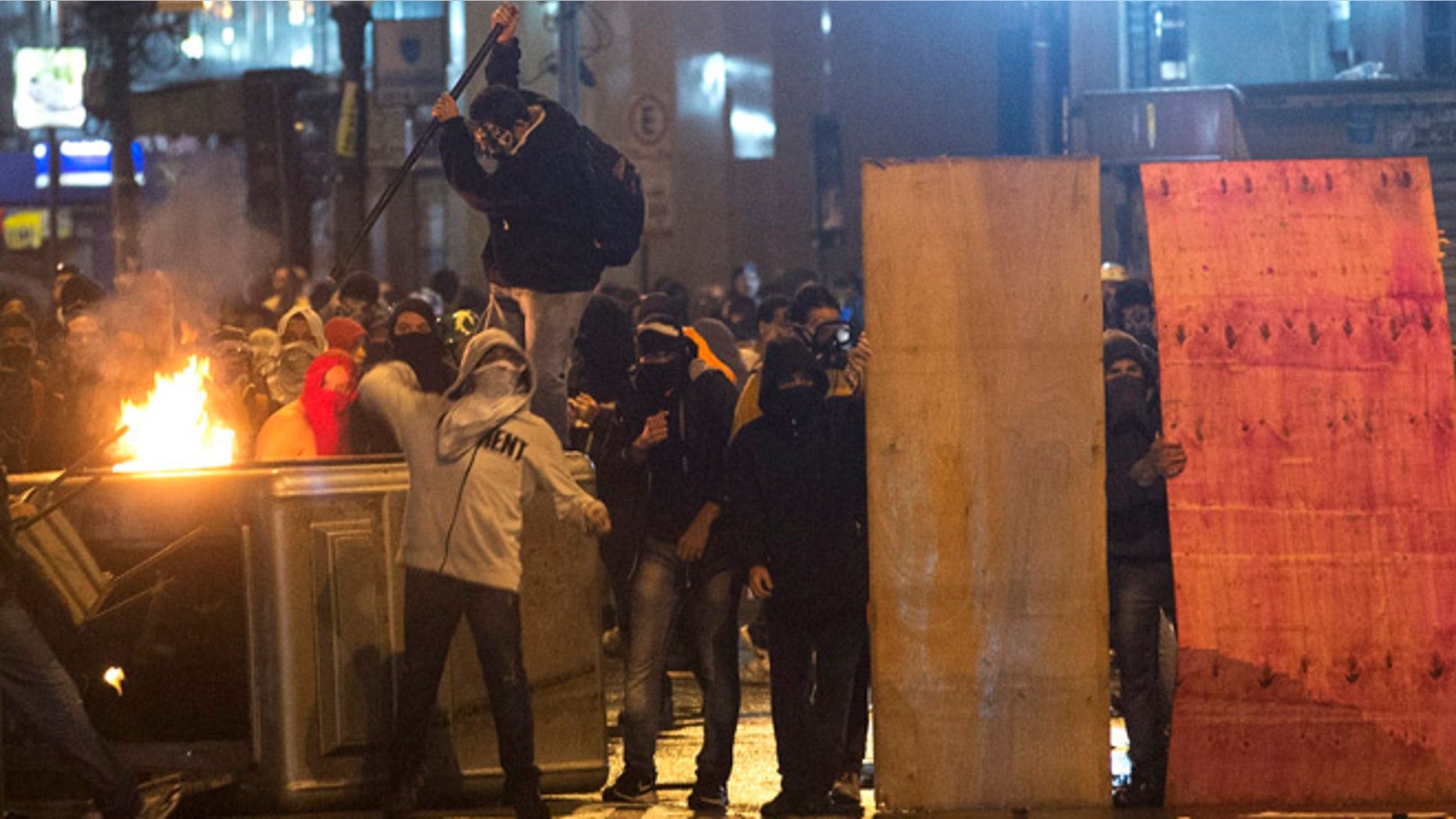 Oct. 7, 2013: Demonstrators with their faces covered throw stones at riot police near the Cinelandia square after a march in support of teachers on strike in Rio de Janeiro, Brazil. Teachers have been on strike demanding better pay for almost two months.
