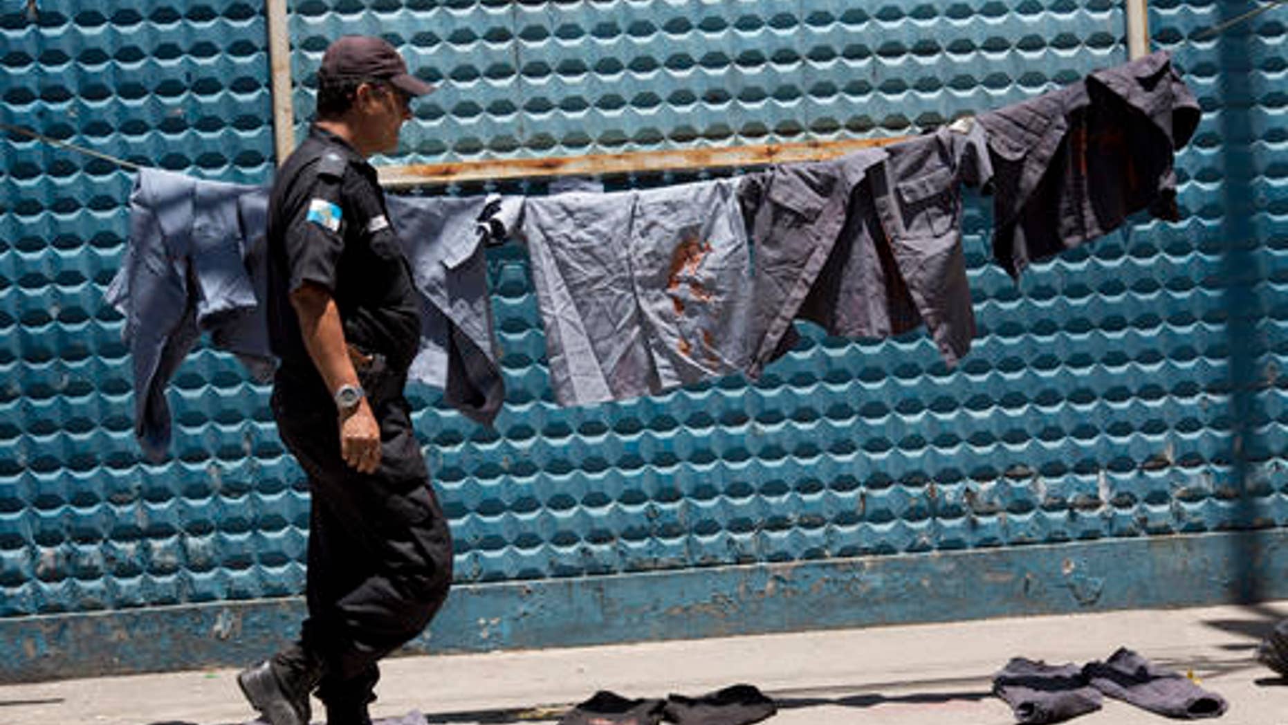 A police officer walks next to uniforms painted with red ink to symbolize blood during a protest in Rio, Brazil, Feb 10, 2017.