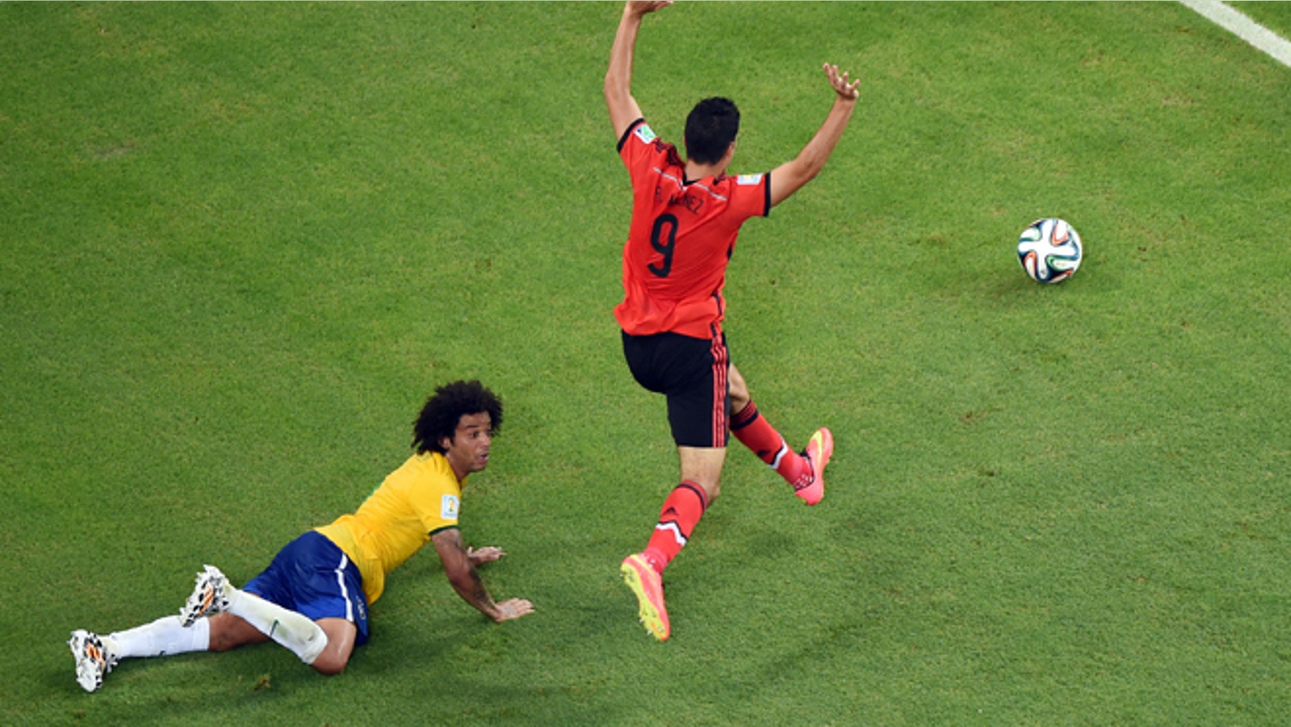 June 17, 2014: Brazil's Marcelo falls in the penalty box as Mexico's Raul Jimenez raises his arms during the group A World Cup soccer match between Brazil and Mexico at the Arena Castelao in Fortaleza, Brazil.