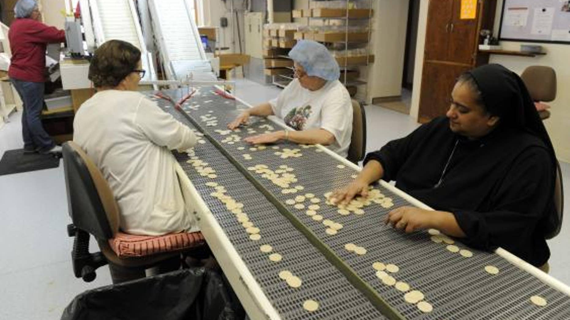 Dec. 18, 2014: Altar Bread Manager Sister Lynn Marie D'Souza (R) helps lay workers look for imperfections on some of the wheat-based communion wafers at the Benedictine Sisters of Perpetual Adoration monastery in Clyde Missouri.