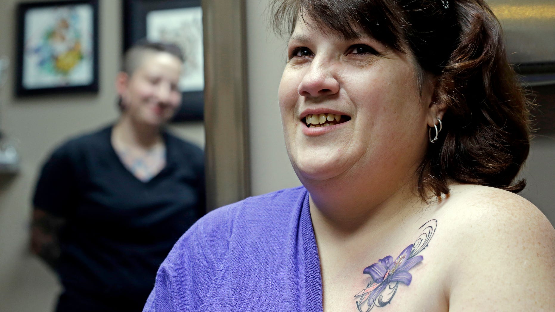 In this Wednesday, Dec. 17, 2014 photo, tattoo artist Ashley Neumann, left, watches as breast cancer survivor Mari Jankowski smiles as she talks about her new tattoo in West Allis, Wis. (AP Photo/Morry Gash)