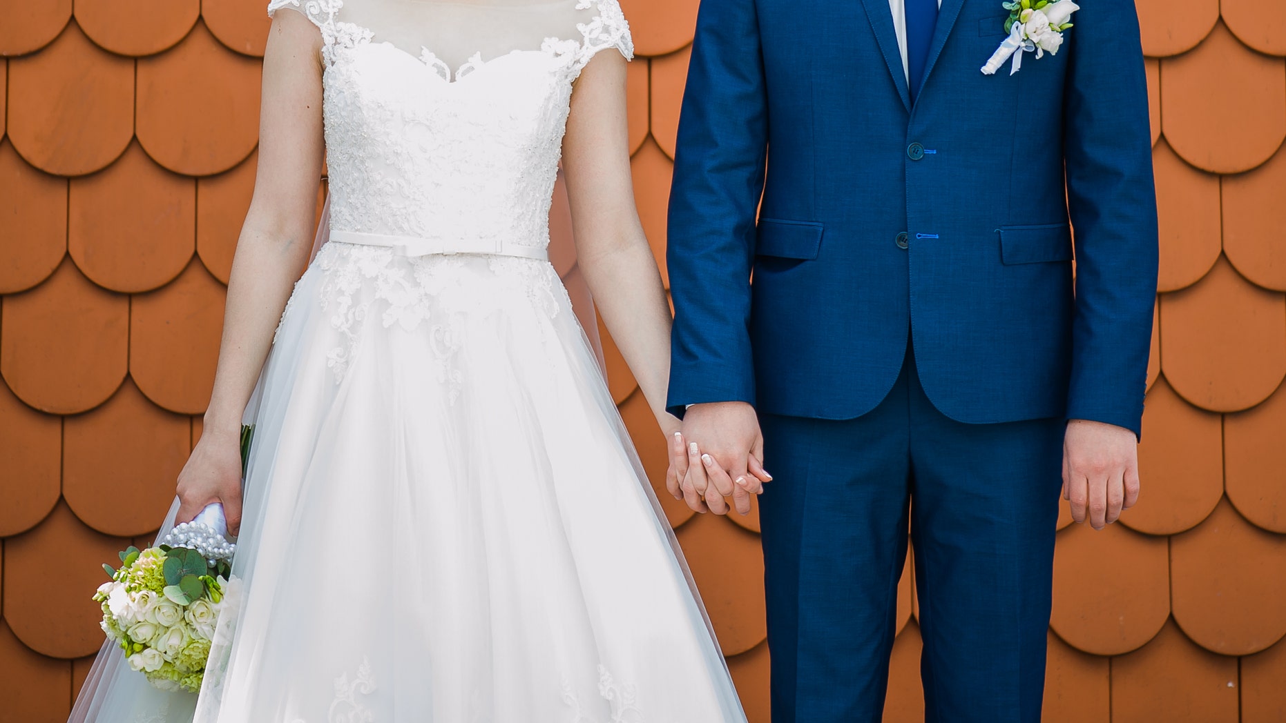Groom holding bride with wedding bouquet before ceremony near church