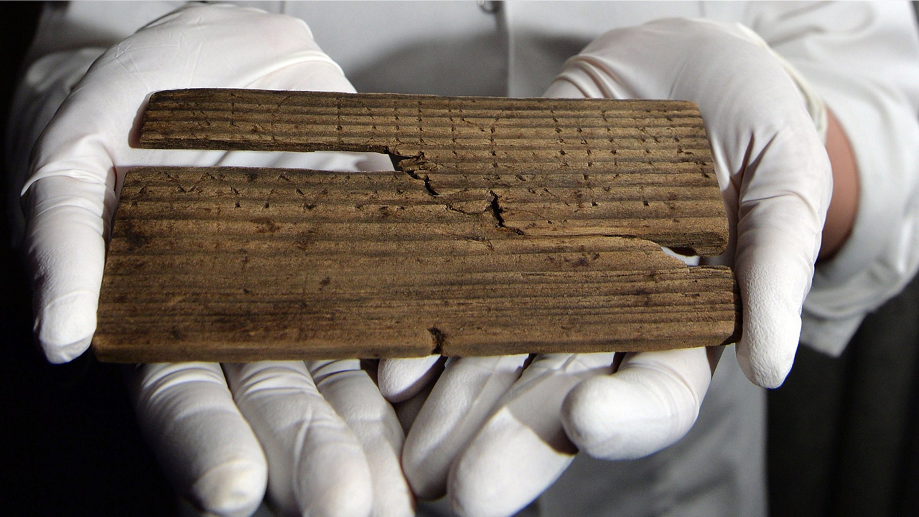 June 1, 2016: Luisa Duarte, a conservator for the Museum of London, holds a piece of wood with the Roman alphabet written on it.