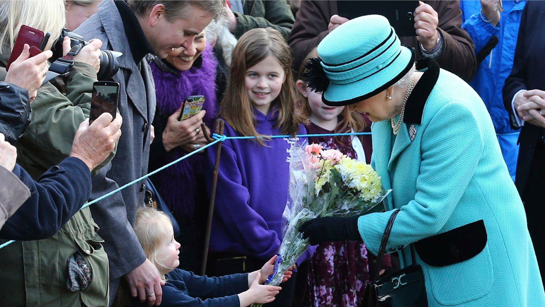 Britain's Queen Elizabeth II stops to receive flowers from 3-year old Jessica Atfield, after the queen and her husband Duke of Edinburgh, attended a church service at St Peter and St Paul church in West Newton, England, Sunday Feb. 5, 2017.