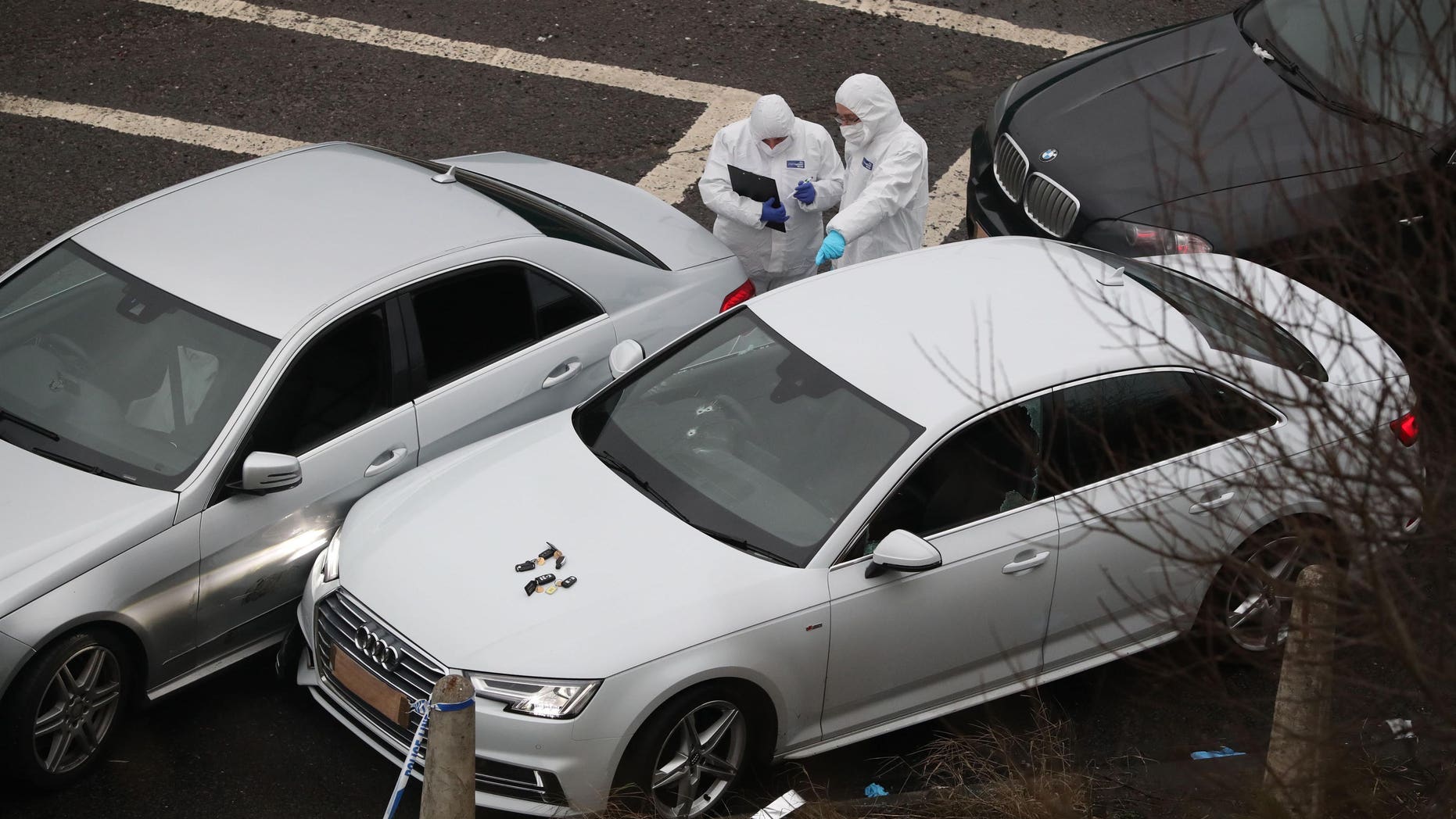 Police forensic officers examine a silver Audi with bullet holes in the windscreen at the scene near the M62 motorway in Huddersfield, England, early Tuesday Jan. 3, 2017. An unidentified man died in a police shooting Monday evening during a police operation, with no other details released by the authorities. (Peter Byrne / PA via AP)