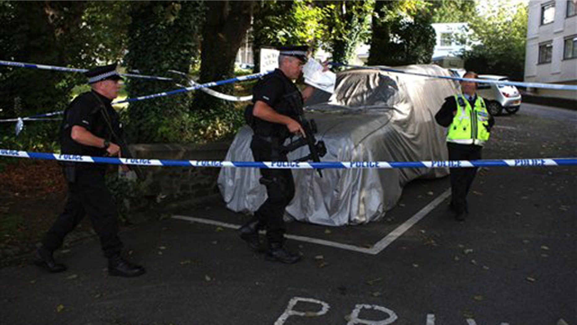 Armed police walk through the grounds of Victoria Crescent in St Helier, Jersey, Monday Aug. 15, 2011. A man was arrested on suspicion of stabbing six people to death, including three children, on the British island of Jersey in what was the deadliest crime in the community's living memory, police said. (AP Photo/Steve Parsons, PA) UNITED KINGDOM OUT NO SALES NO ARCHIVE