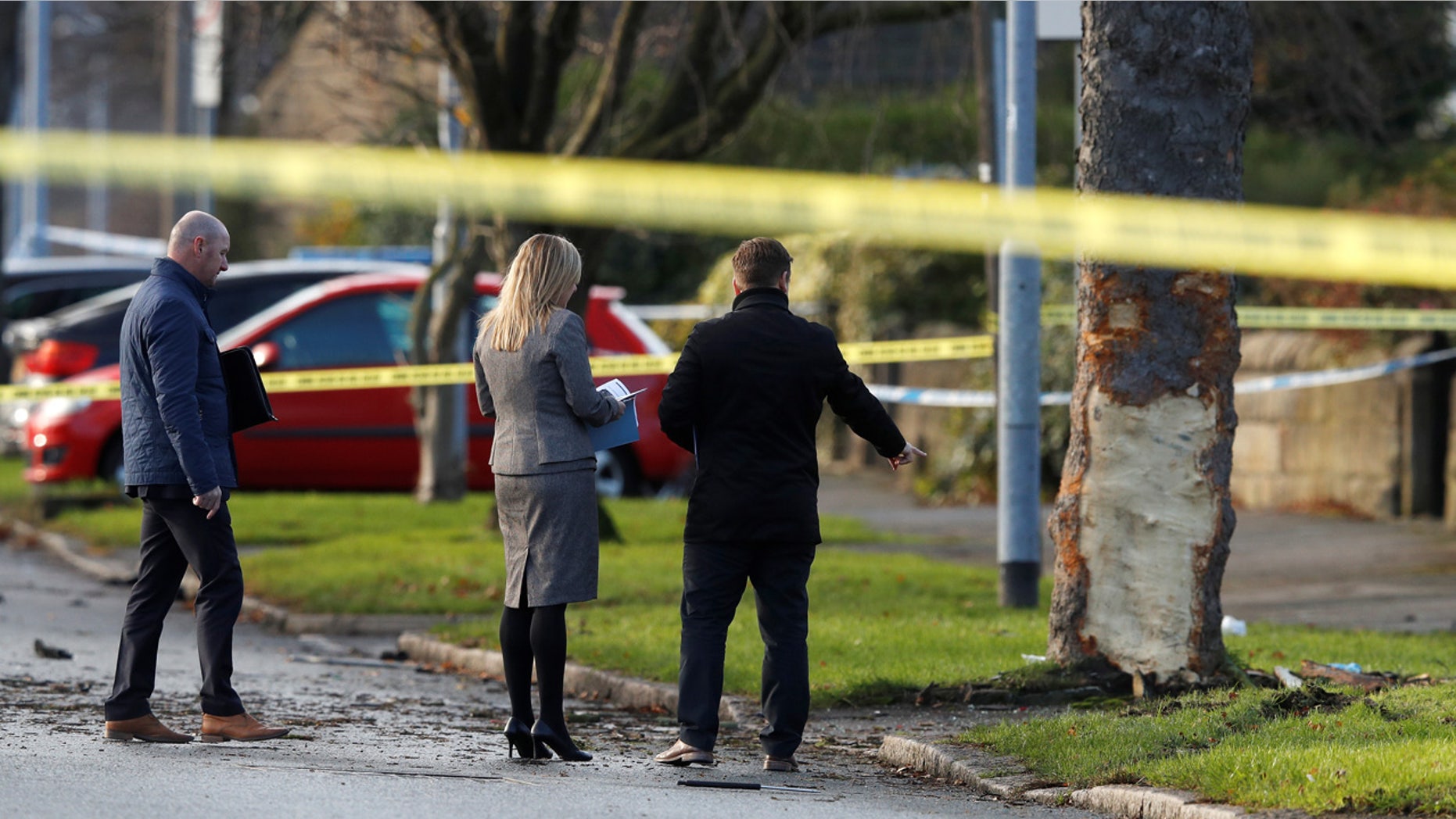 Investigators work behind police tape at the scene where a stolen car crashed into a tree, leaving 5 people dead, including 3 children, in Leeds, Britain,