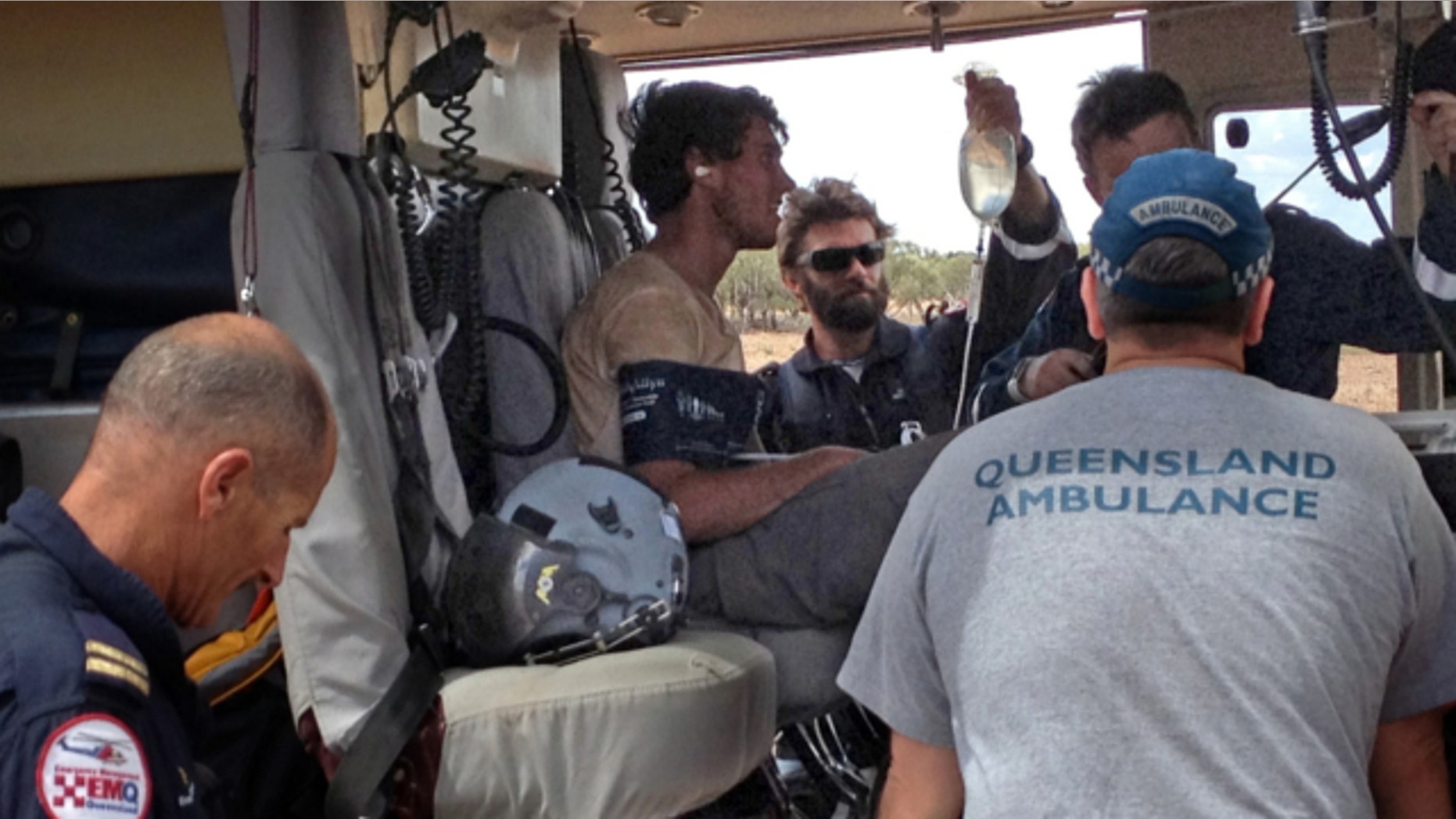 Feb. 15, 2013: British backpacker Sam Derry-Woodhead, second left, sits in a rescue helicopter as he is tended to by ambulance personnel, outside of Longreach, Australia.