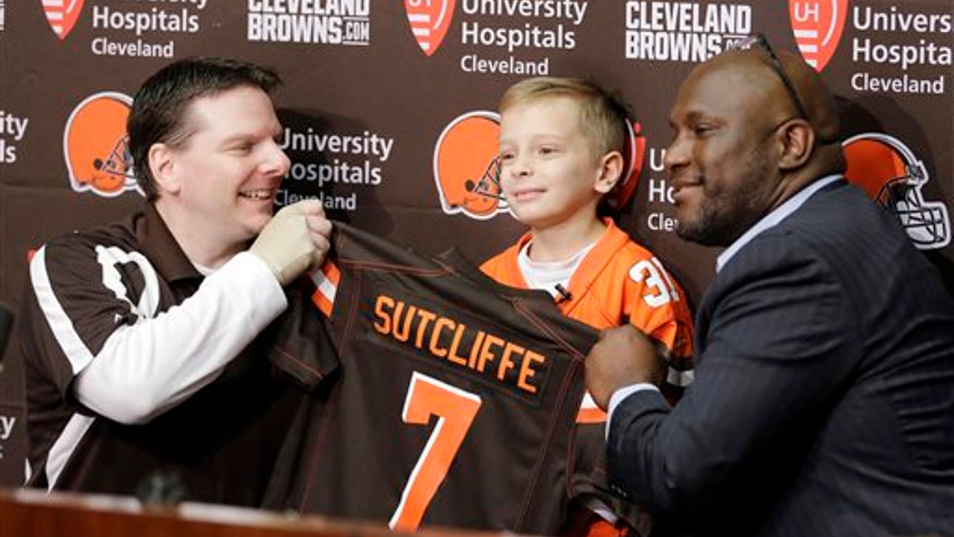 Derek Sutcliffe, left, and Cleveland Browns general manager Ray Farmer, right, hold up a jersey for Dylan Sutcliffe, 9, during an NFL football news conference, Tuesday, June 2, 2015, in Berea, Ohio. (AP Photo/Tony Dejak)