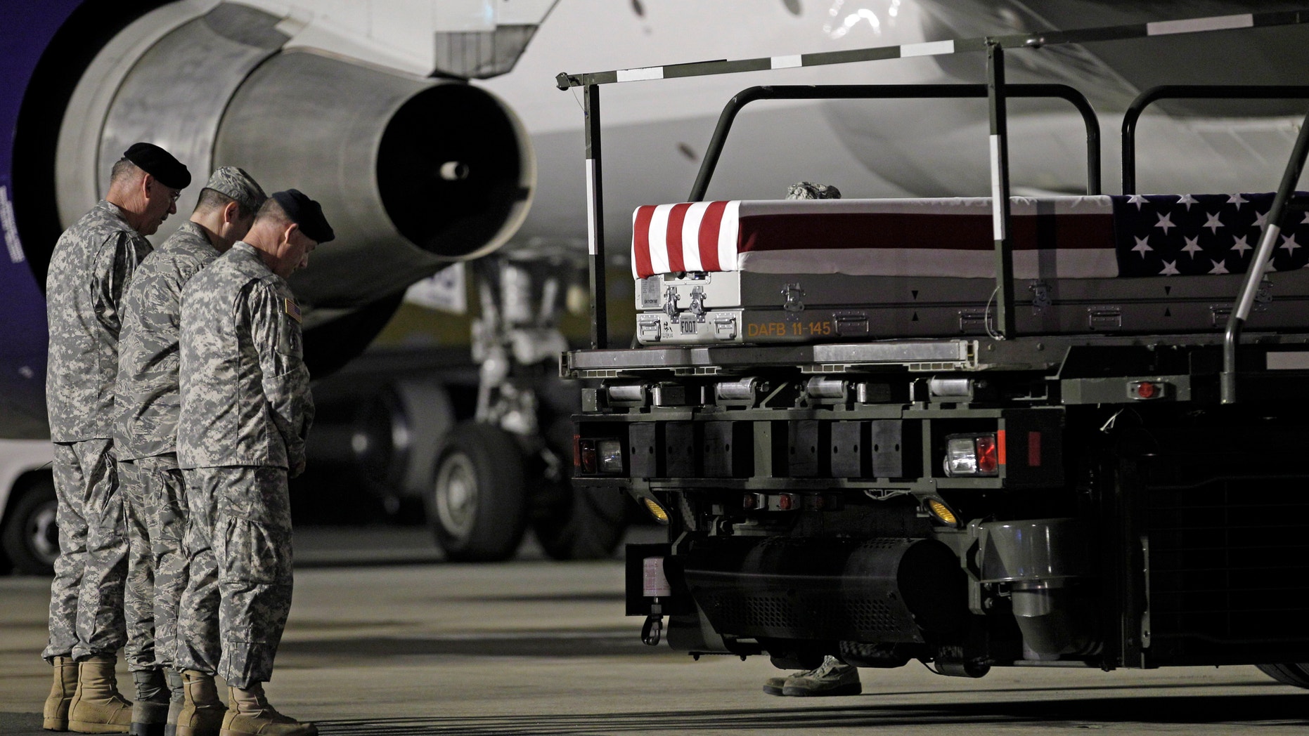 May 3, 2012: Chaplain Col. Dennis Goodwin, left, directs a prayer over the transfer case containing the remains of Army Capt. Bruce K. Clark of Spencerport, N.Y., upon arrival at Dover Air Force Base, Del. The Department of Defense announced the death of Clark who was supporting Operation Enduring Freedom in Afghanistan. (AP)