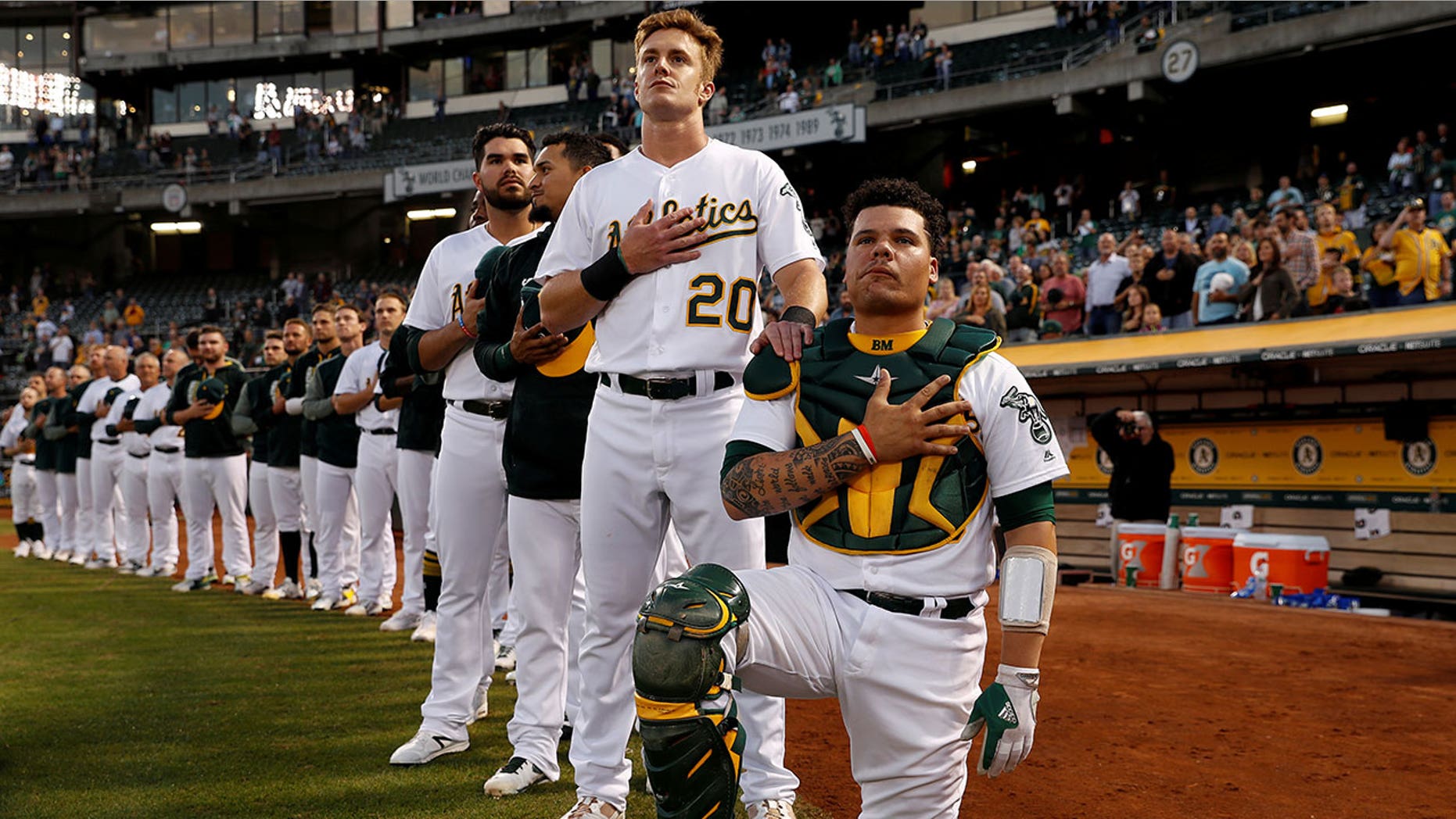 Bruce Maxwell of the Oakland Athletics kneels as teammate Mark Canha #20 places his hand on Maxwell's shoulder during the singing of the national anthem on September 25.