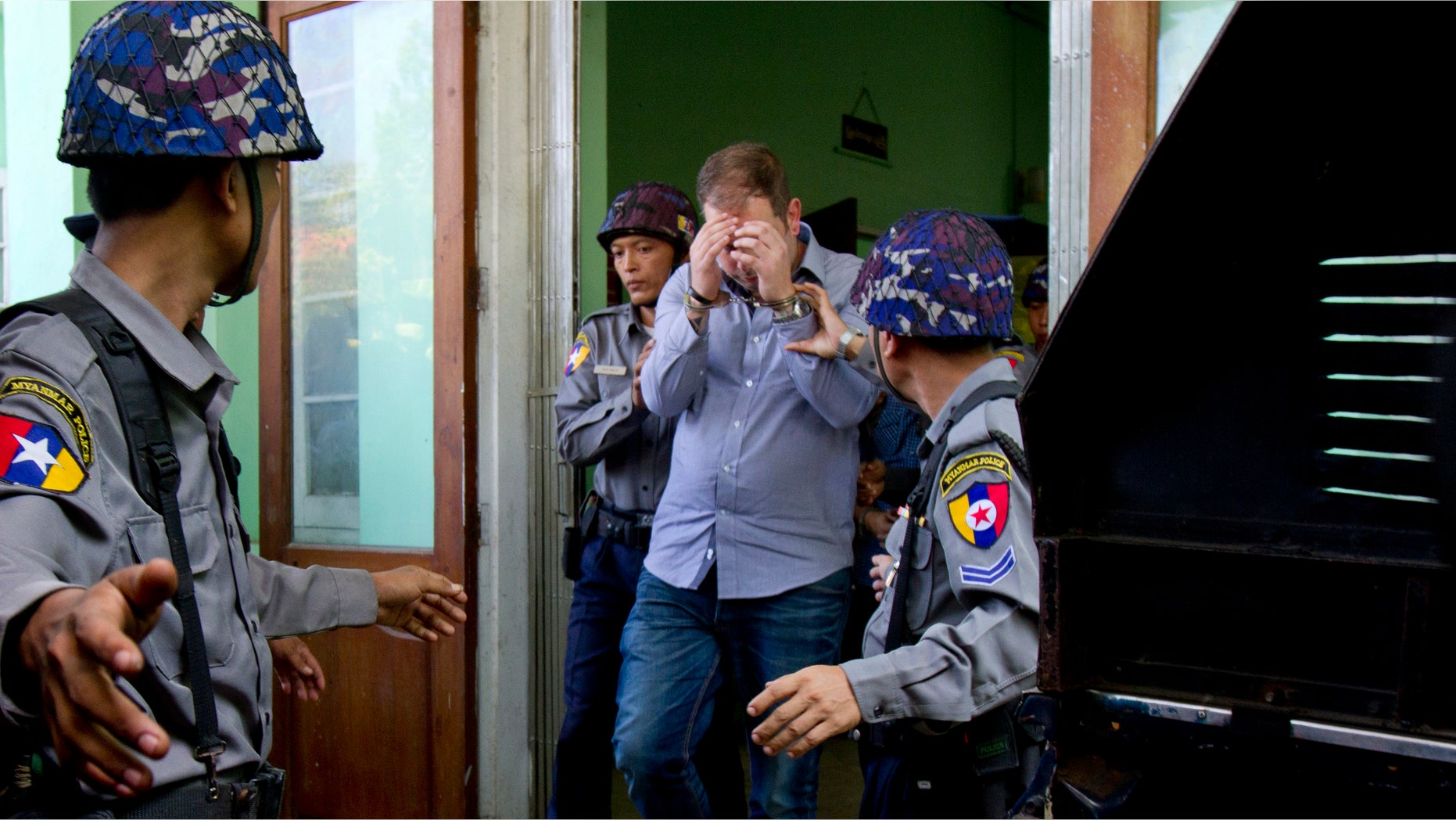 Dec. 11, 2014: New Zealand citizen Philip Blackwood, center, is escorted by Myanmar police officers following a court appearance in Yangon, Myanmar
