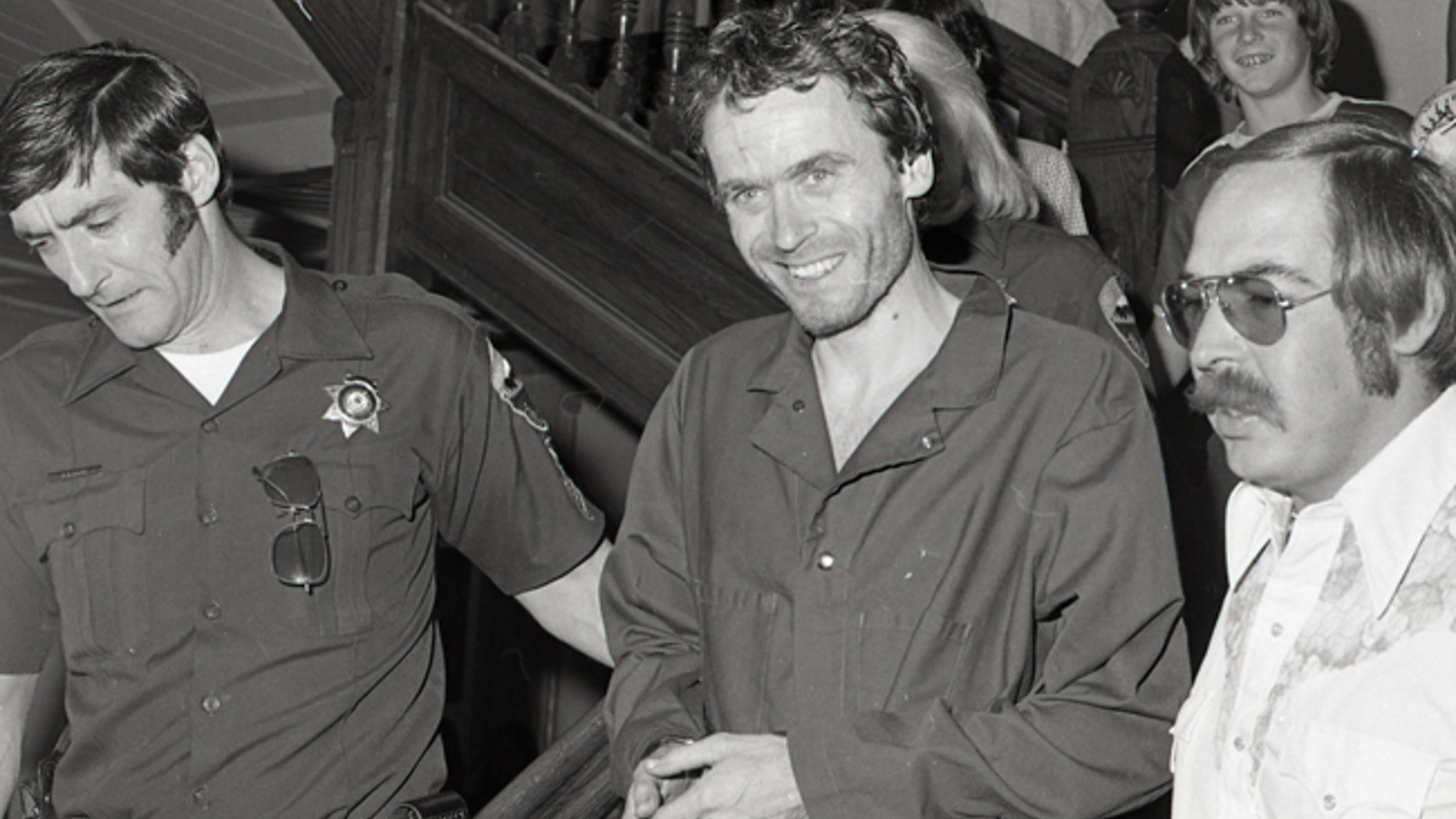In this 1977 photo serial killer Ted Bundy, center, is escorted out of court in Pitkin County, Colo.