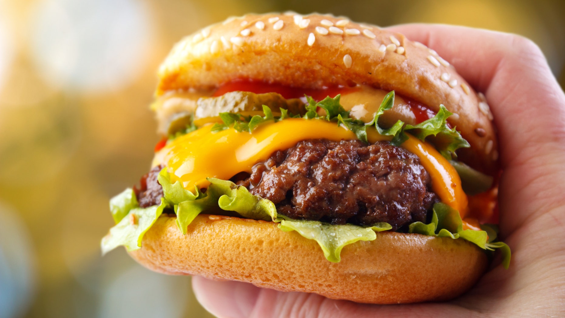 Hand holding a warm homemade hamburger in outdoors