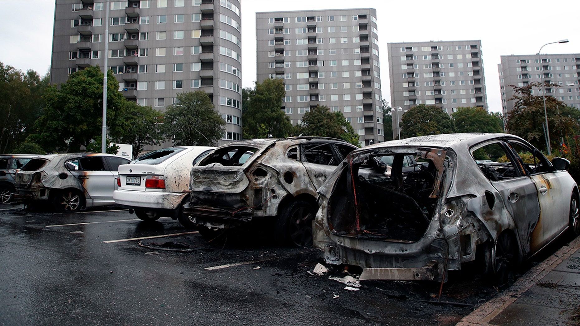 Burned cars parked at Frolunda Square in Gothenburg, Tuesday, Aug. 14, 2018. Masked youth torched dozens of cars overnight in Sweden and threw rocks at police, prompting an angry response from the prime minister, who on Tuesday spoke of an "extremely organized" night of vandalism. (Adam Ihse/TT via AP)