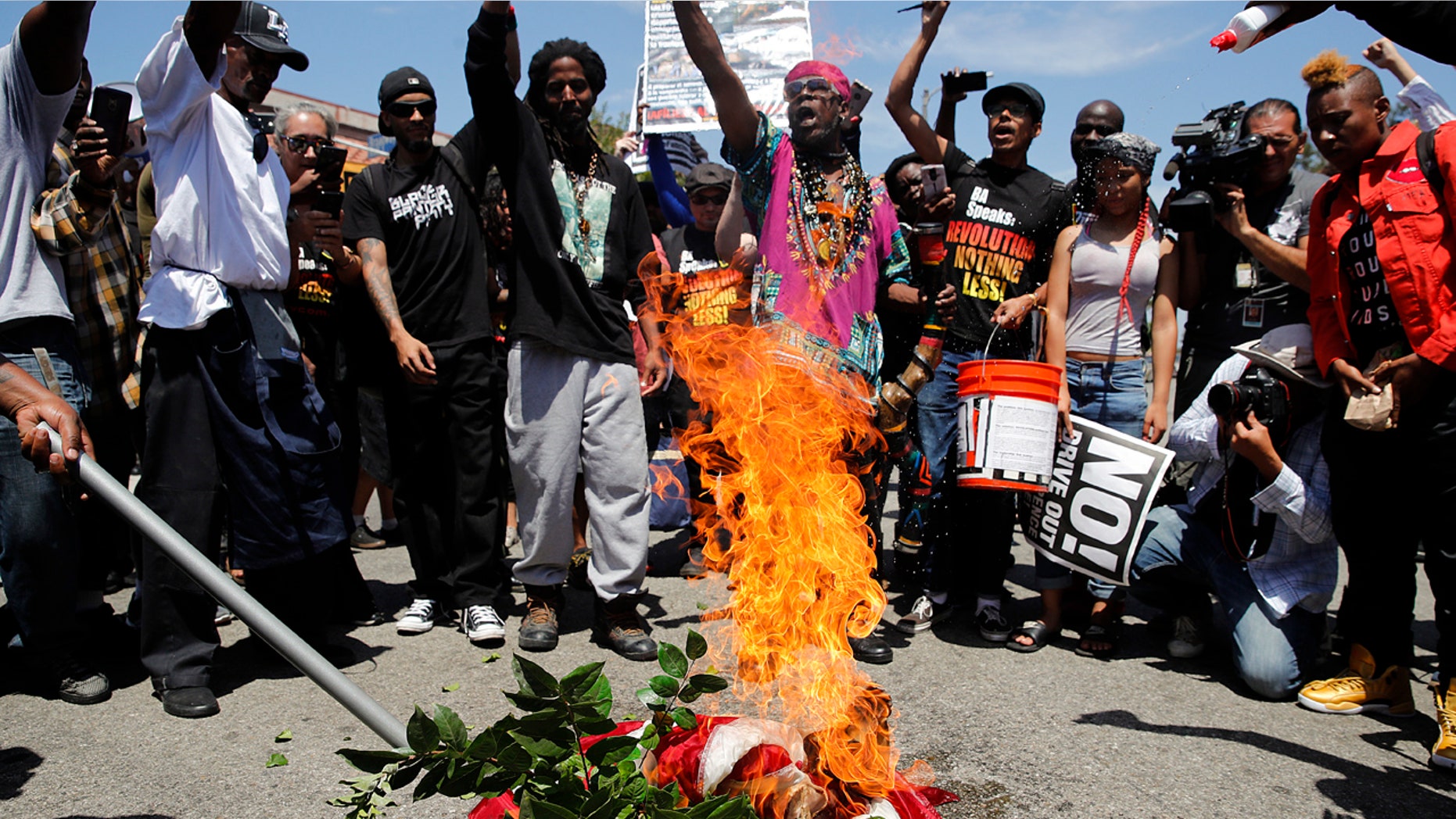 People chant slogans as they burn a U.S. flag outside the Los Angeles office of U.S. Rep. Maxine Waters, Thursday, July 19, 2018, in Los Angeles.