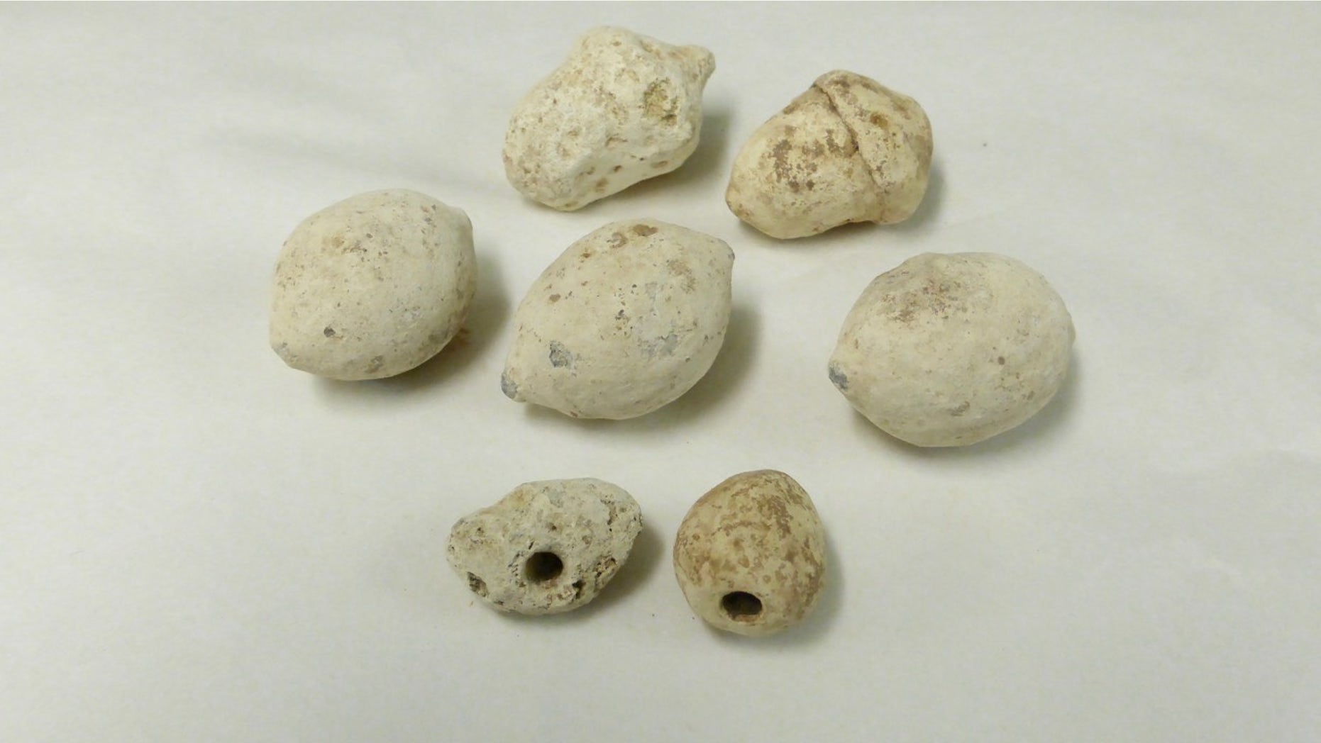Some of the Roman sling bullets found at the Burnswark Hill battle site in Scotland. The two smallest bullets, shown at the bottom of this image, are drilled with a hole that makes them whistle in flight.