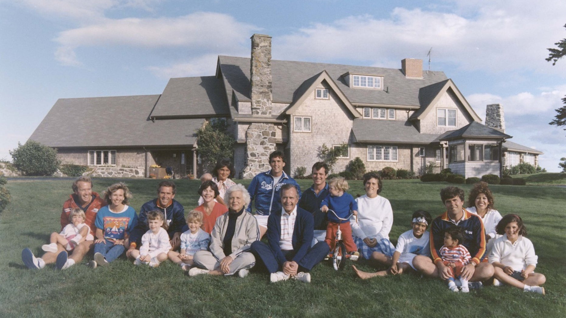 Portrait of the Bush family sitting in front of their home in Kennebunkport, Maine. BACK ROW: Maragret Bush (Marvin's wife), holding daughter Marshall, Marvin Bush, Bill LeBlond (Doro's Husband). FRONT ROW: Neil Bush holding son Pierce, Sharon (Neil's wife), George W. Bush holding daughter Barbara Bush, George Bush, Sam LeBlond (Doro's son), Doro Bush LeBlond, George P.