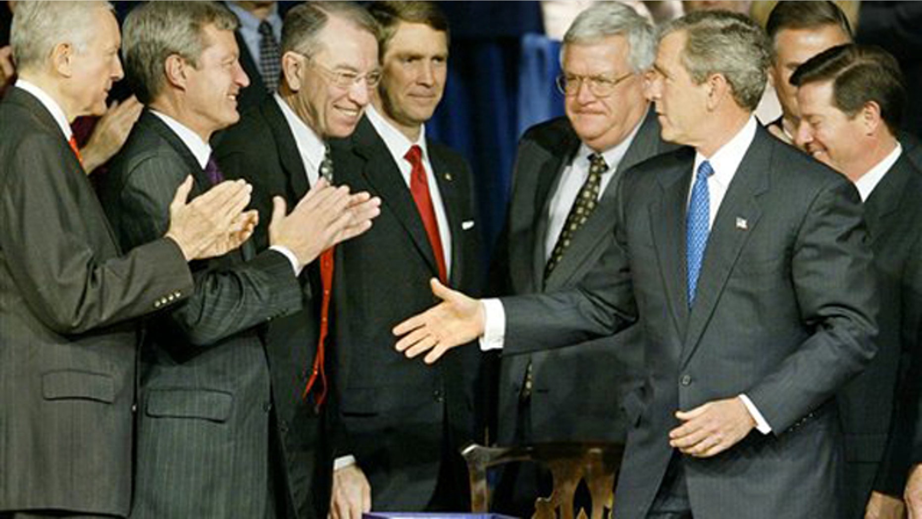 In this Dec. 8, 2003, file photo then-President George W. Bush greets applauding congressional leaders as he signs into law the Medicare prescription drug benefit in Washington.