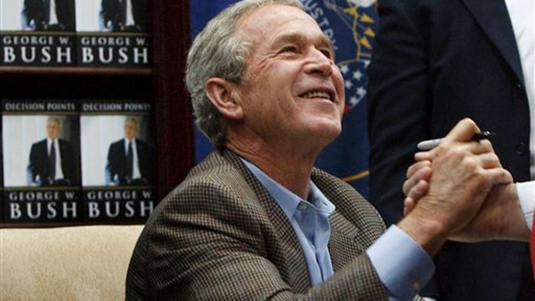 Former President George W. Bush shakes hands with a man after autographing a copy of his memoir Friday, Nov. 19, 2010, in Sandy, Utah. More than 1,000 people were lined up waiting for an autographed copy of the former president's memoir, "Decision Points."