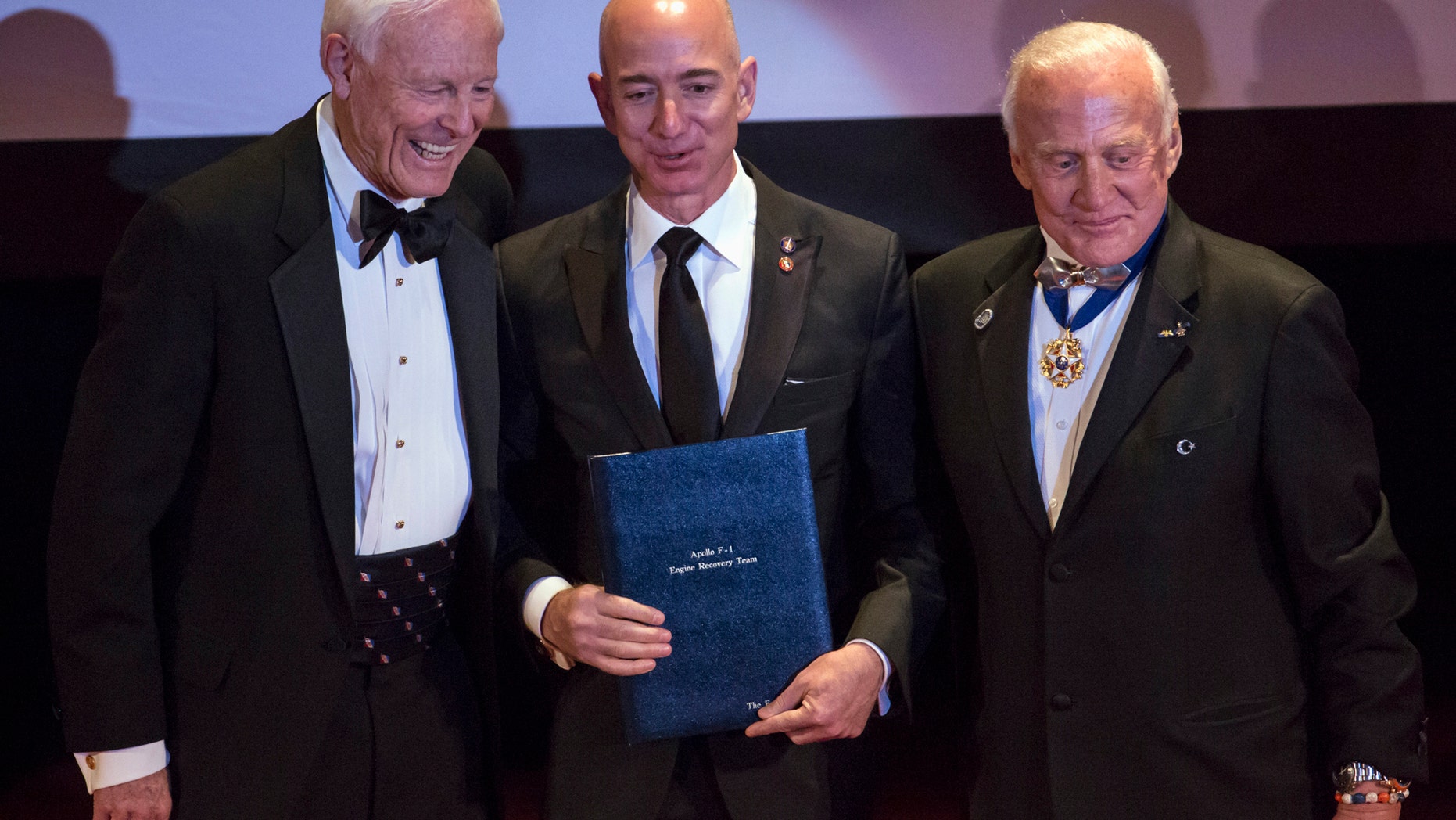 File photo: Explorers Club President Alan Nichols (L) and Astronaut Edwin "Buzz" Aldrin (R) present the Citation of Merit to Amazon CEO and Chairman Jeff Bezos (C) and the Apollo F-1 Search and Recovery Team, at the 110th Explorers Club Annual Dinner at the Waldorf Astoria in New York March 15, 2014. (REUTERS/Andrew Kelly)
