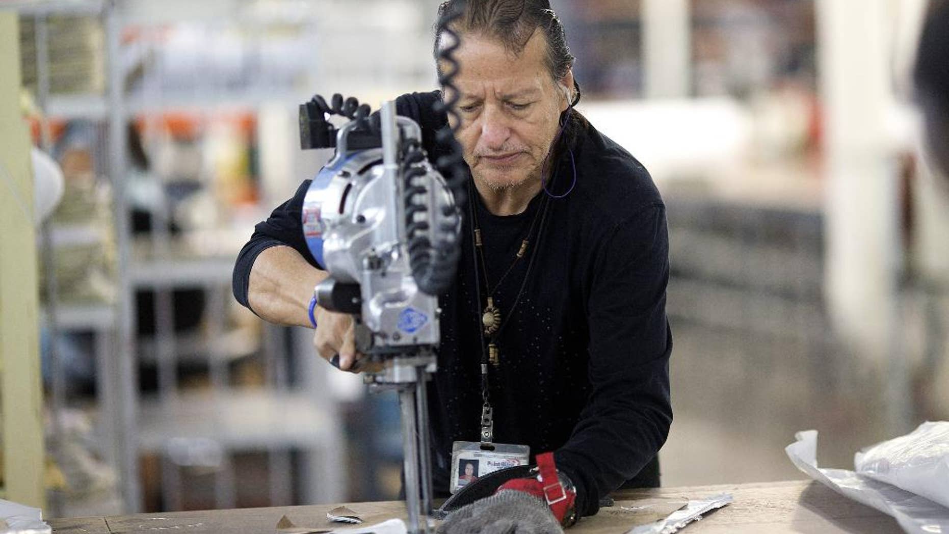 In this Sept. 19, 2014 photo, Adolfo Garzon cuts pieces for body armor at the Point Blank Body Armor factory in Pompano Beach, Fla. The Labor Department releases fourth-quarter productivity data on Thursday, March 5, 2015. (AP Photo/J Pat Carter)