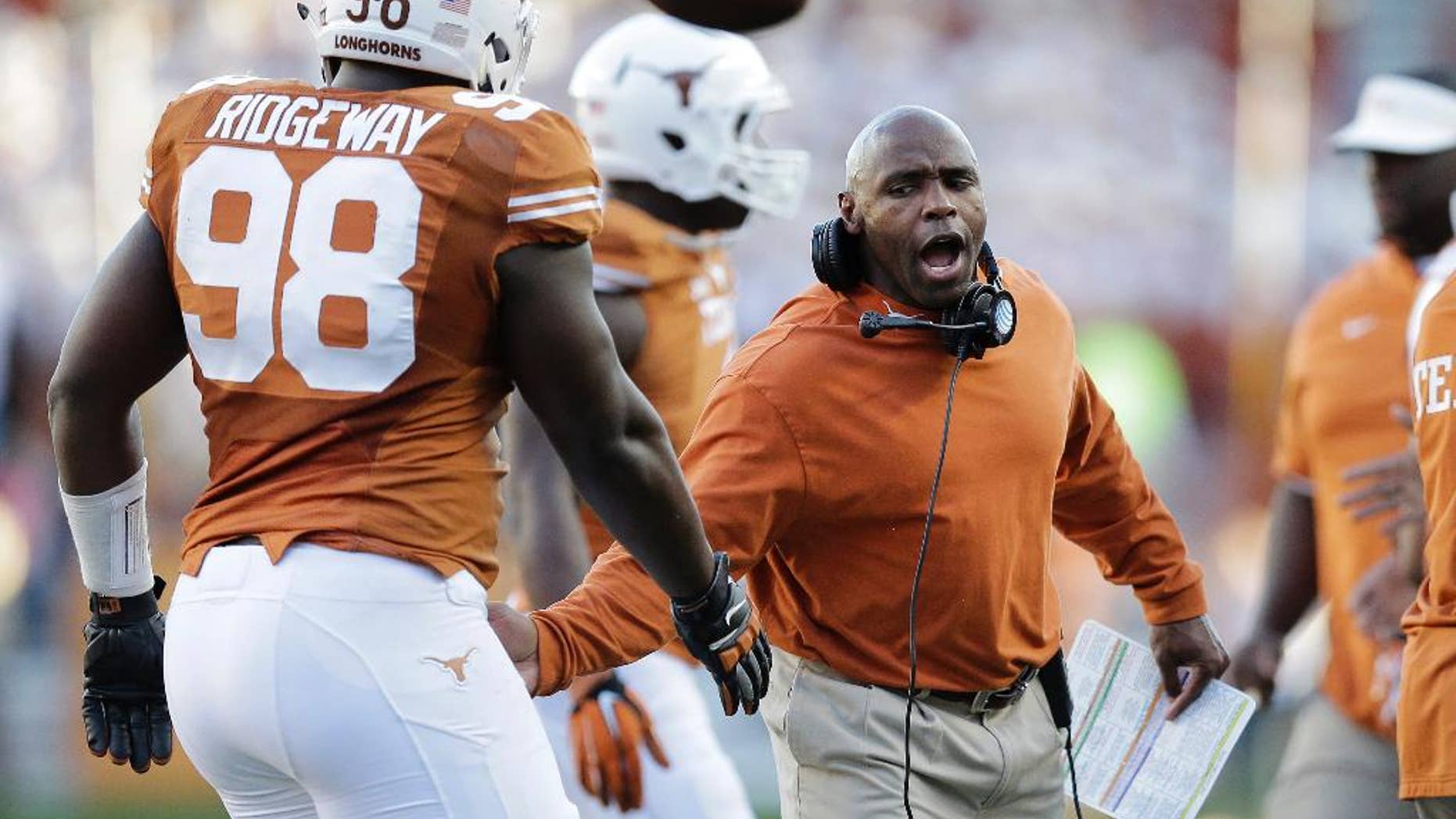 FILE - In this Nov. 8, 2014, file photo, Texas Longhorns head coach Charlie Strong, right, congratulates players as they walk off the field during the second half of an NCAA college football game against West Virginia in Austin, Texas. BOUND- Texas is bowl bound. That seemed such an unlikely scenario for first-year coach Charlie Strong when the Longhorns got shut out a month ago and were sinking fast. (AP Photo/Eric Gay, File)