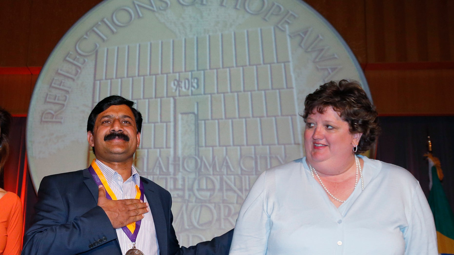 Ziauddin Yousafzai, left, reacts after receiving the Reflections of Hope Award from Kari Watkins, right, executive director of the Oklahoma City National Memorial & Museum, in Oklahoma City, Monday, May 13, 2013. The 2013 Reflections of Hope Award was presented to Yousafzai and his daughter Malala Yousafzai, who was not present. Malala was shot in the head by a Taliban gunman in an assassination attempt that drew attention worldwide to the struggle for women's rights in her homeland. (AP Photo/Sue Ogrocki)