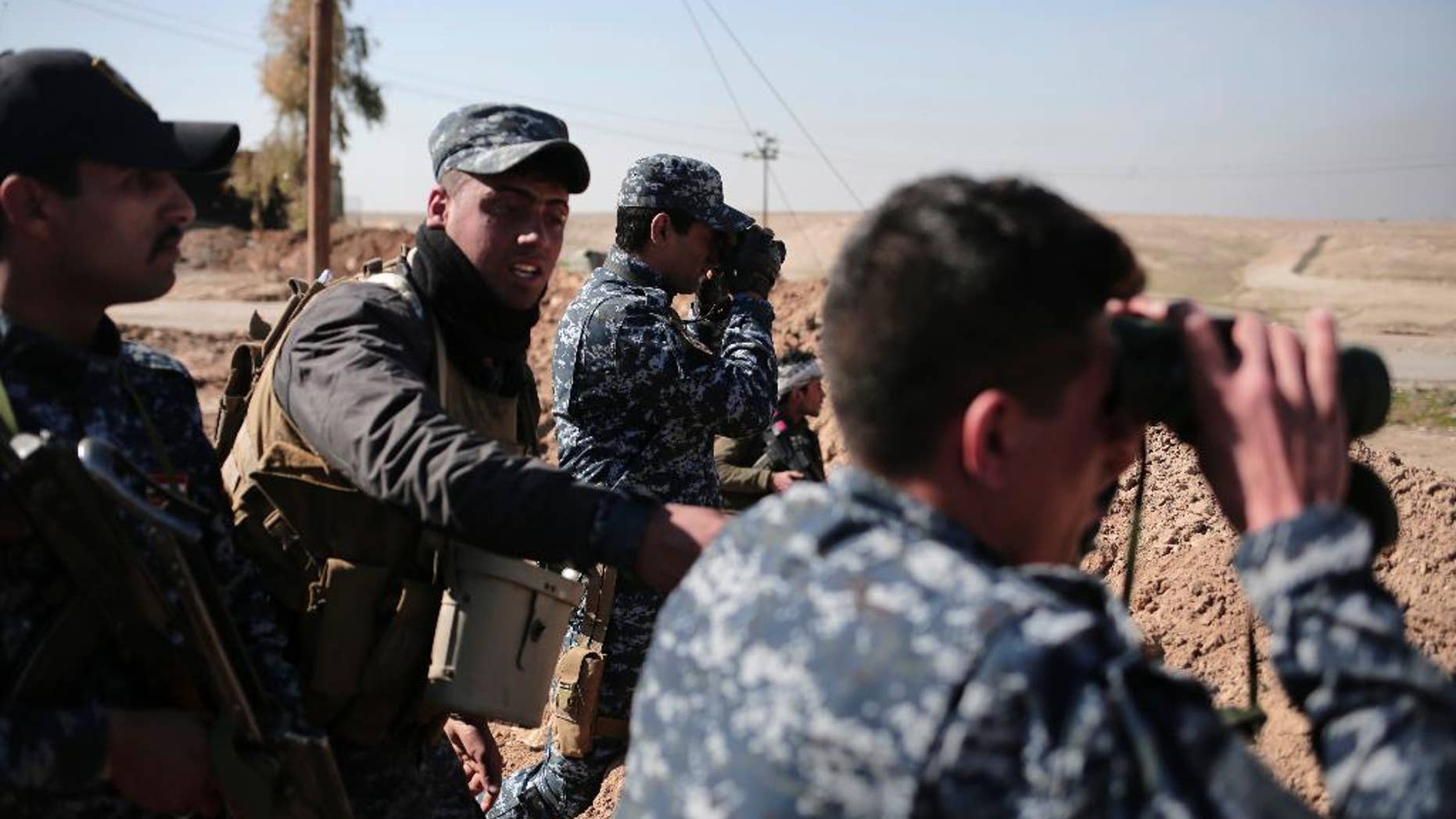 Federal police officers look towards Islamic State group territory as civilians flee the area, in the town of Abu Saif, Iraq, Tuesday, Feb. 21, 2017. A military spokesman says Iraqi forces are consolidating their gains south of Mosul ahead of moving deeper into the city's Islamic State-held western half. The spokesman of the Joint Military Operation Command, Brig. Gen. Yahya Rasool, told The Associated Press that nearly 123 square kilometers -- about 47 square miles -- have been taken south of Mosul since the new push started on Sunday. (AP Photo/Bram Janssen)
