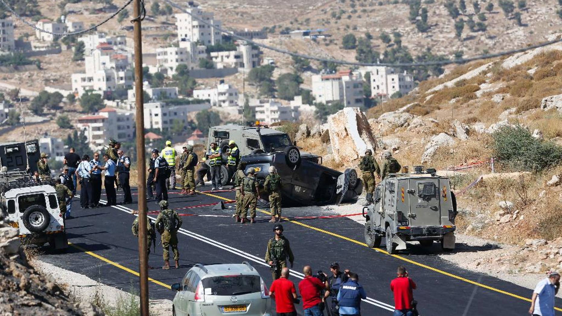 FILE - In this Friday, July 1, 2016, file photo, Israeli soldiers secure the scene of a car crash after a shooting attack near Hebron, West Bank, Friday, July 1, 2016. A few years ago, Islam al-Bayed spent seven months in an Israeli prison for allegedly throwing stones at Israeli troops. Now, the 26-year-old Palestinian man has become an unlikely symbol of coexistence after rescuing an Israeli family whose car crashed following a deadly roadside shooting by Palestinian militants in the West Bank. (AP Photo/Nasser Shiyoukhi)