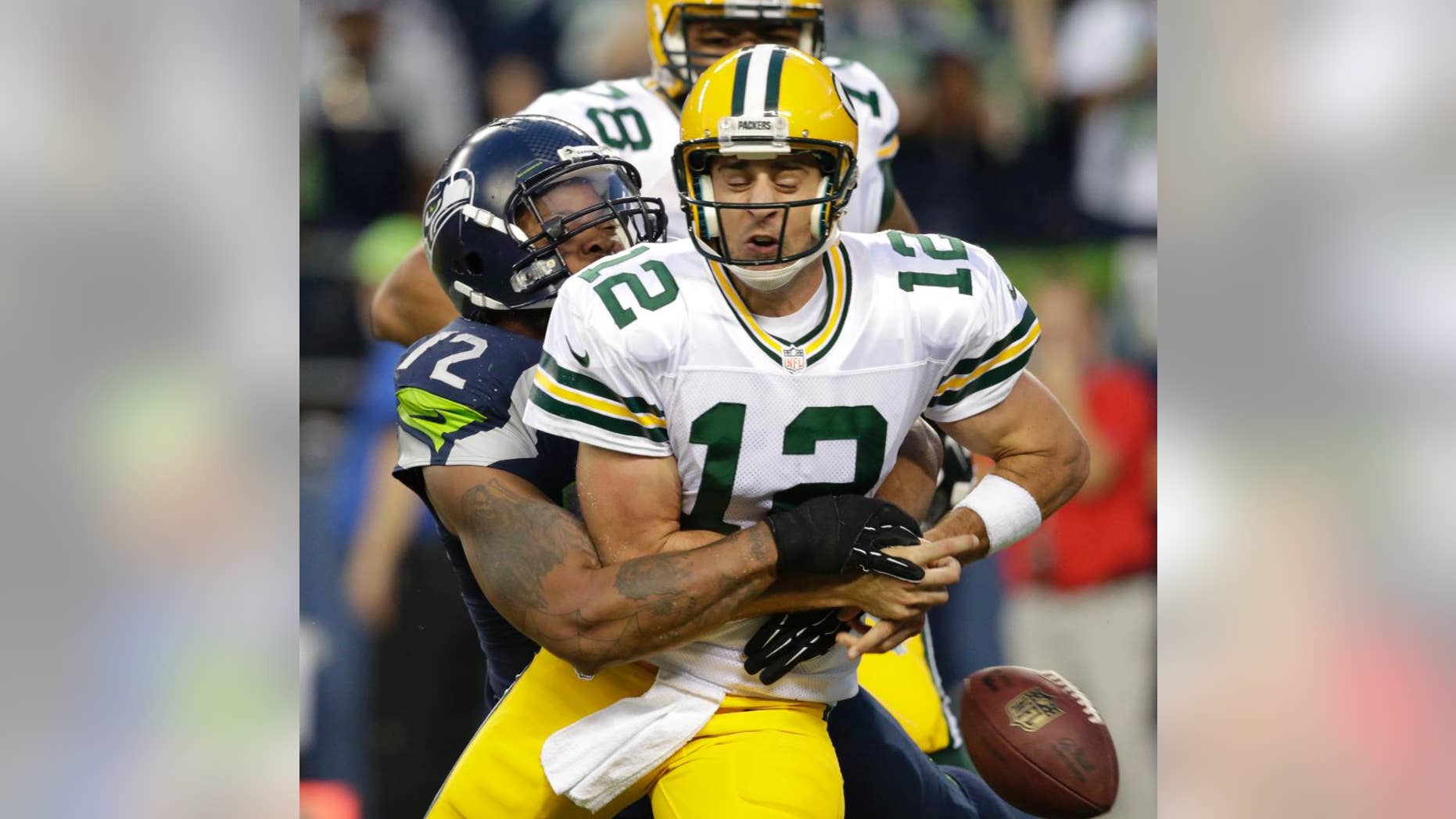 Seattle Seahawks defensive end Michael Bennett forces Green Bay Packers quarterback Aaron Rodgers to fumble in the second half of an NFL football game, Thursday, Sept. 4, 2014, in Seattle. A Packers player recovered the ball in the end zone, but was tackled for a safety on the play. (AP Photo/Scott Eklund)