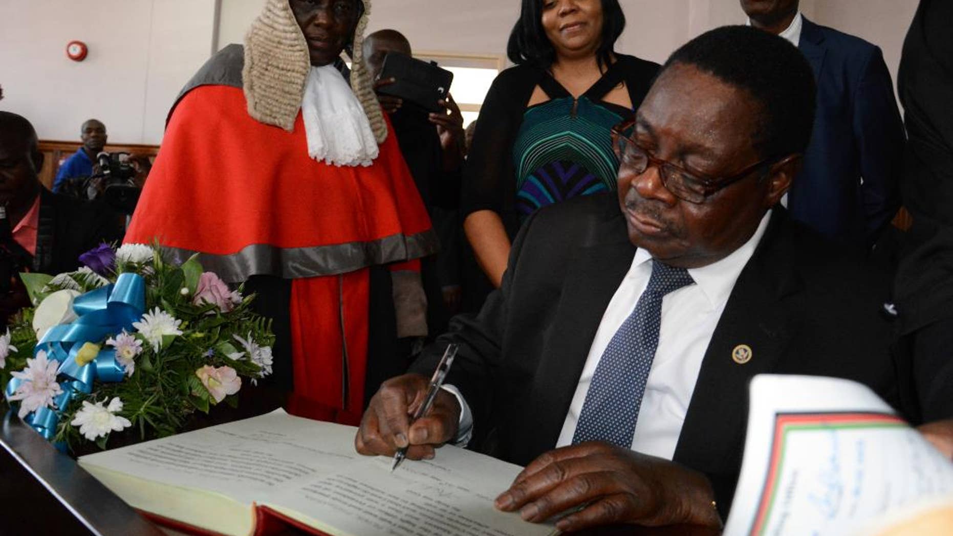 Newly elected Malawian president Peter Mutharika signs the oath book after he was sworn in, at the High Court in Blantyre, Malawi, Saturday May 31, 2014. Malawi's election commission has declared opposition leader Mutharika to be the winner of an election that was marred by scattered unrest and complaints from the president and others that the vote was rigged. (AP Photo/Thoko Chikondi)